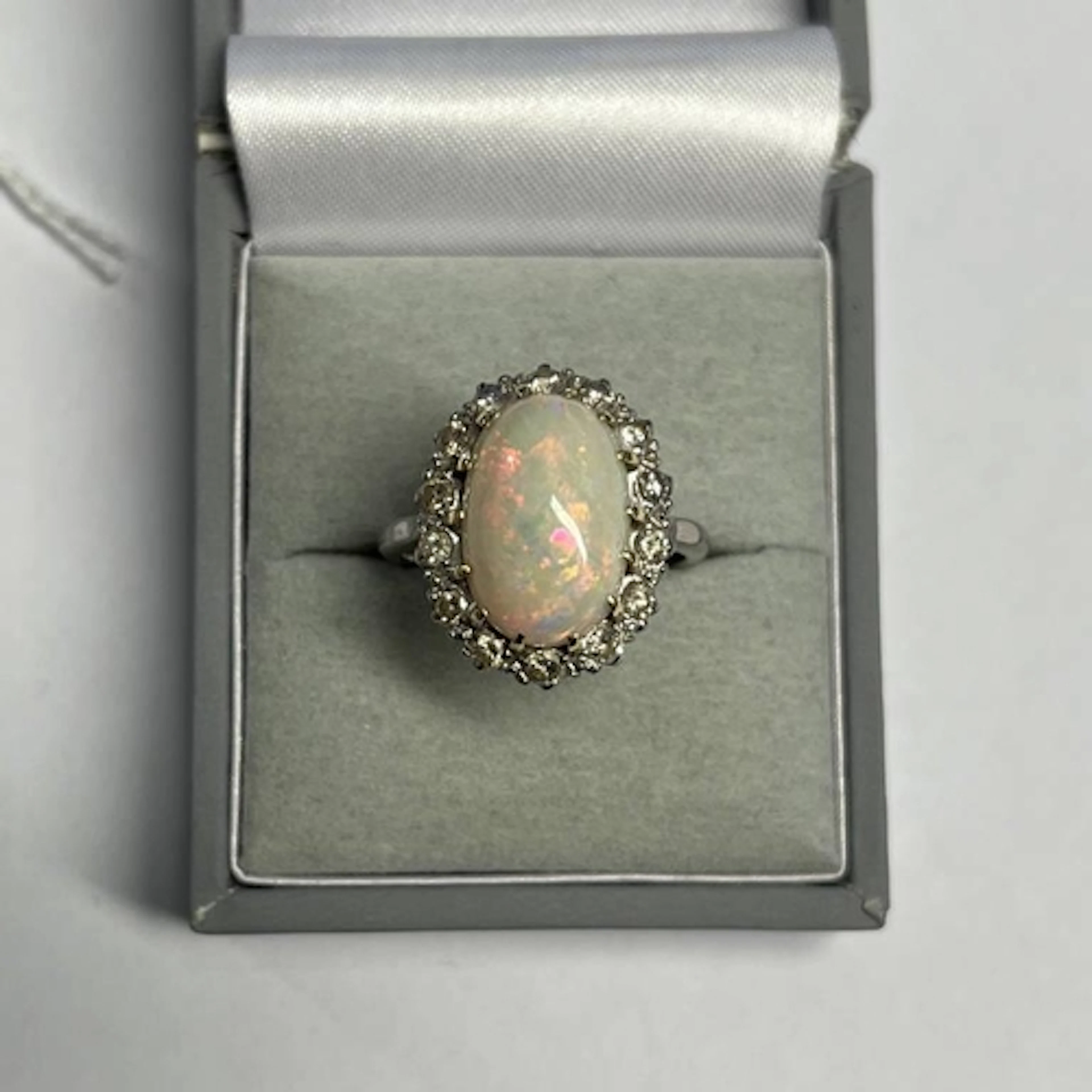OPAL & DIAMOND CLUSTER RING, THE OVAL CABOCHON SET WITH A SU...