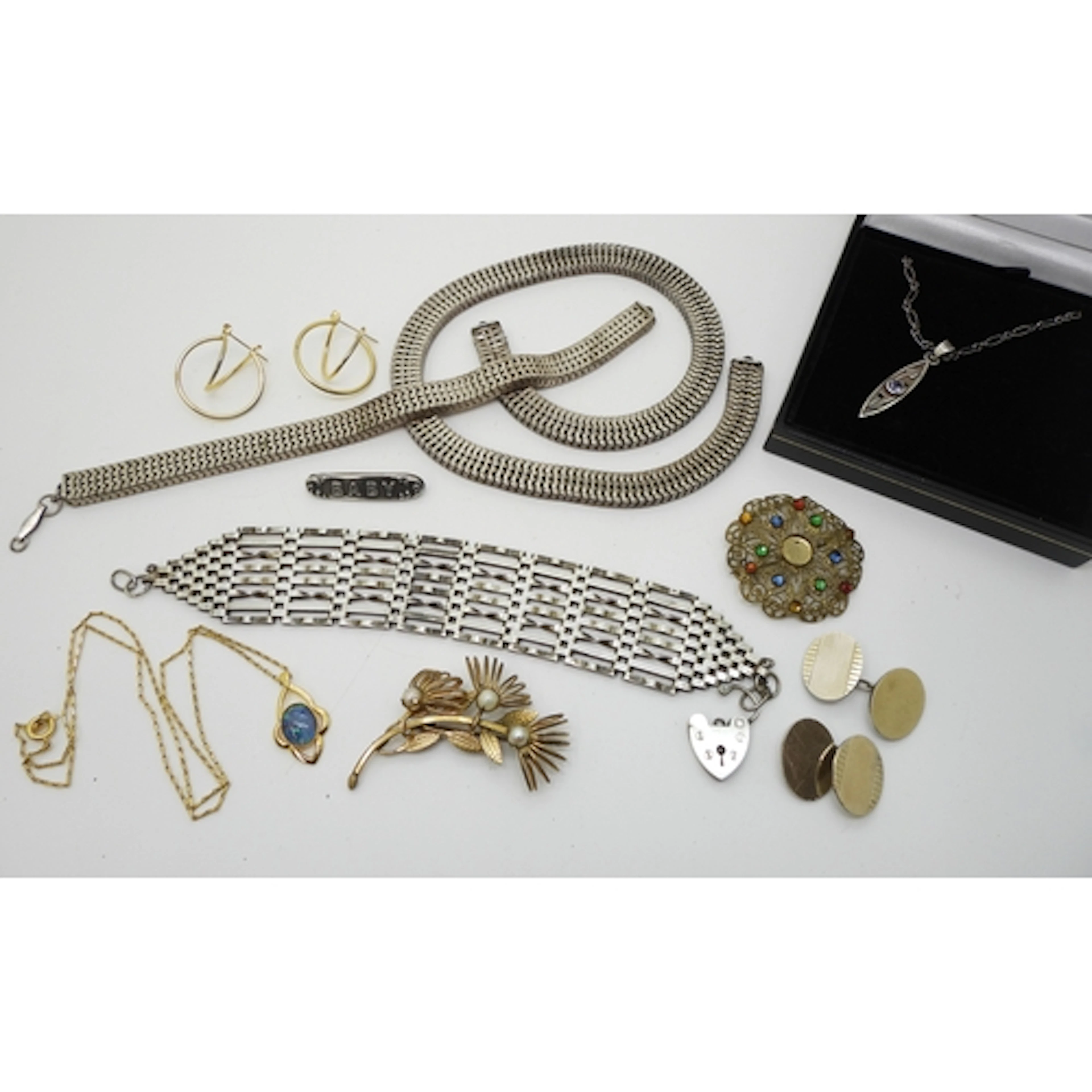 A silver wide gate bracelet with a heart shaped clasp, a sil...