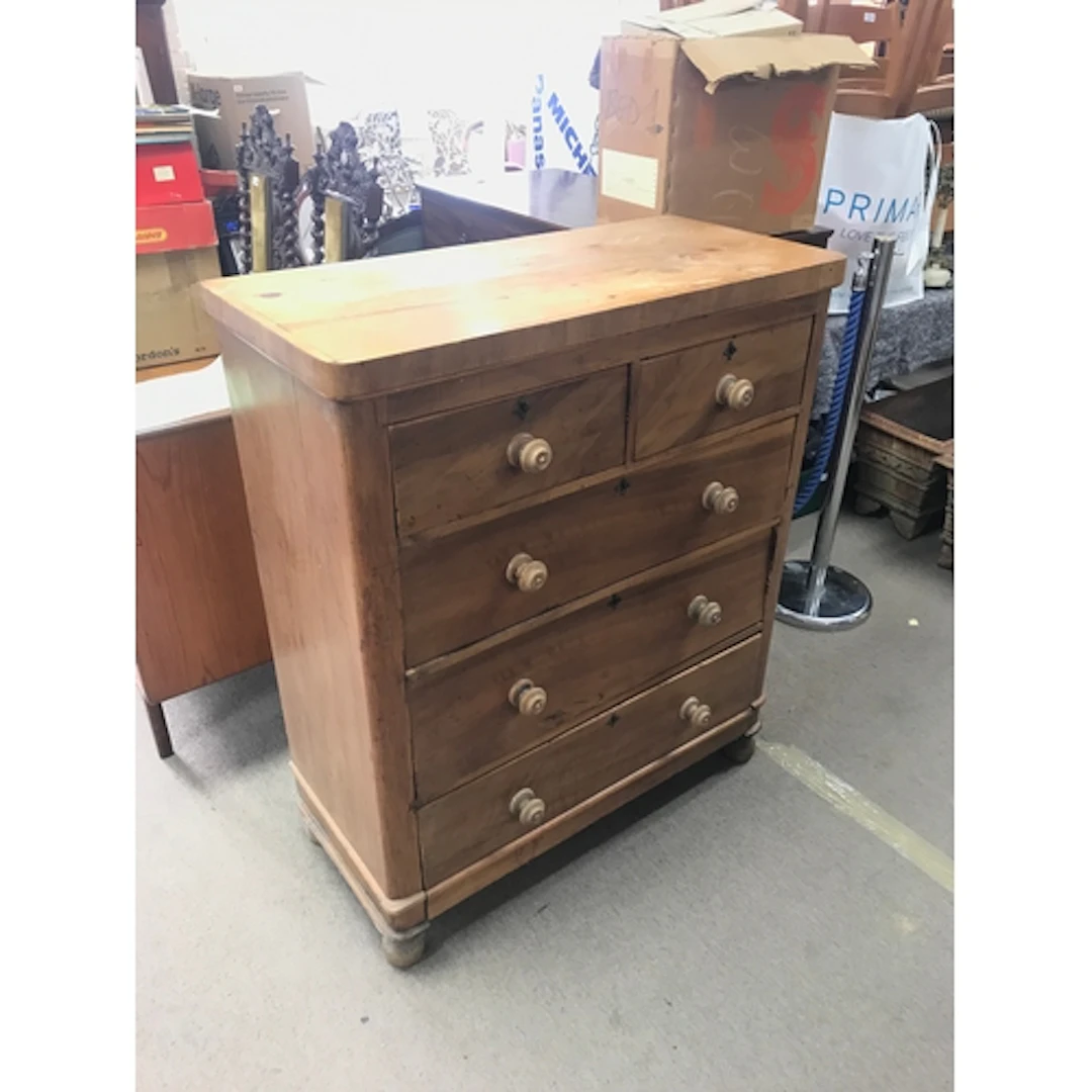 A pine chest of drawers featuring a traditional two-over-thr...