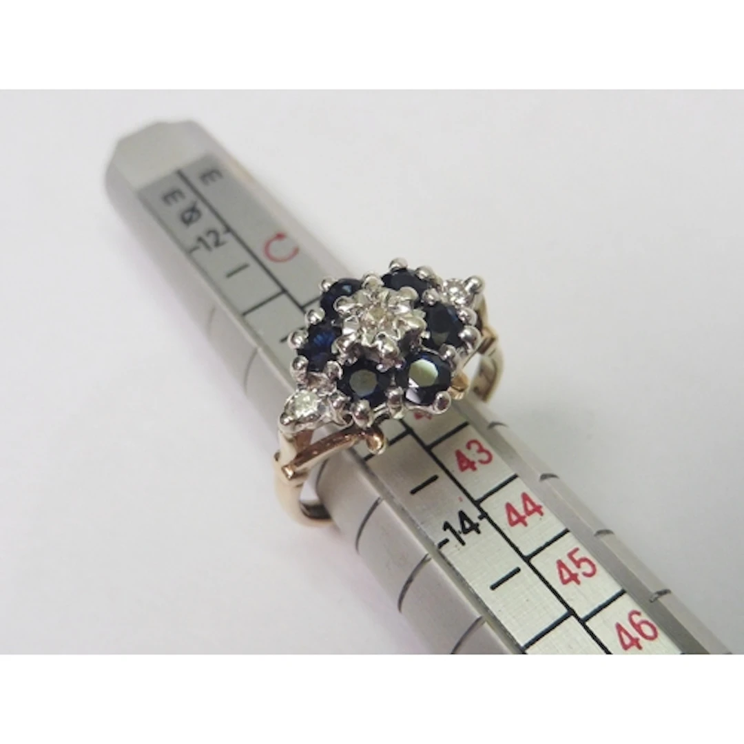 A 9ct gold sapphire and diamond cluster ring. Head 9.5mm ac...