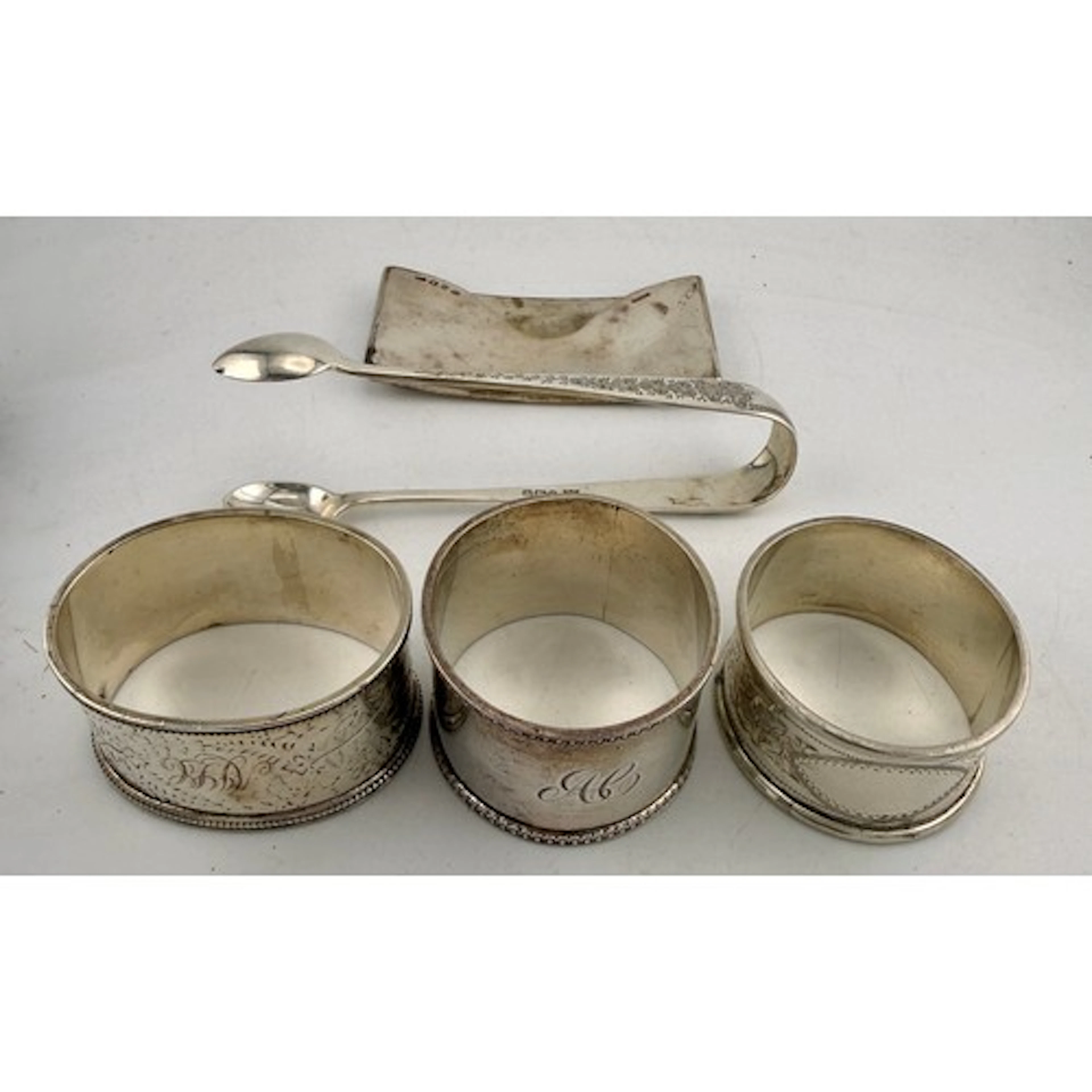 Hallmarked silver to include three napkin rings, sugar tongs...