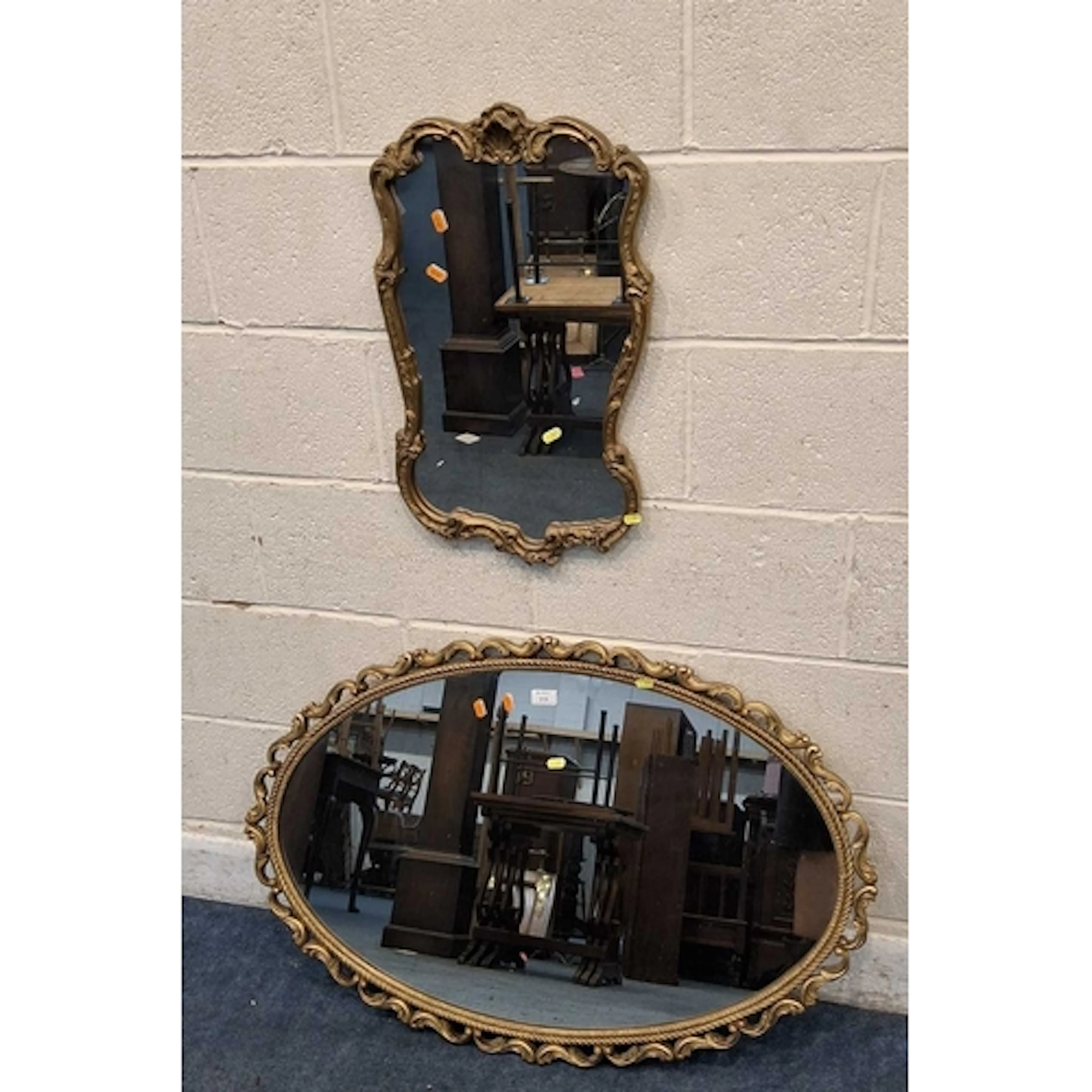 AN OVAL GILT RESIN WALL MIRROR, with scrolled details, along...