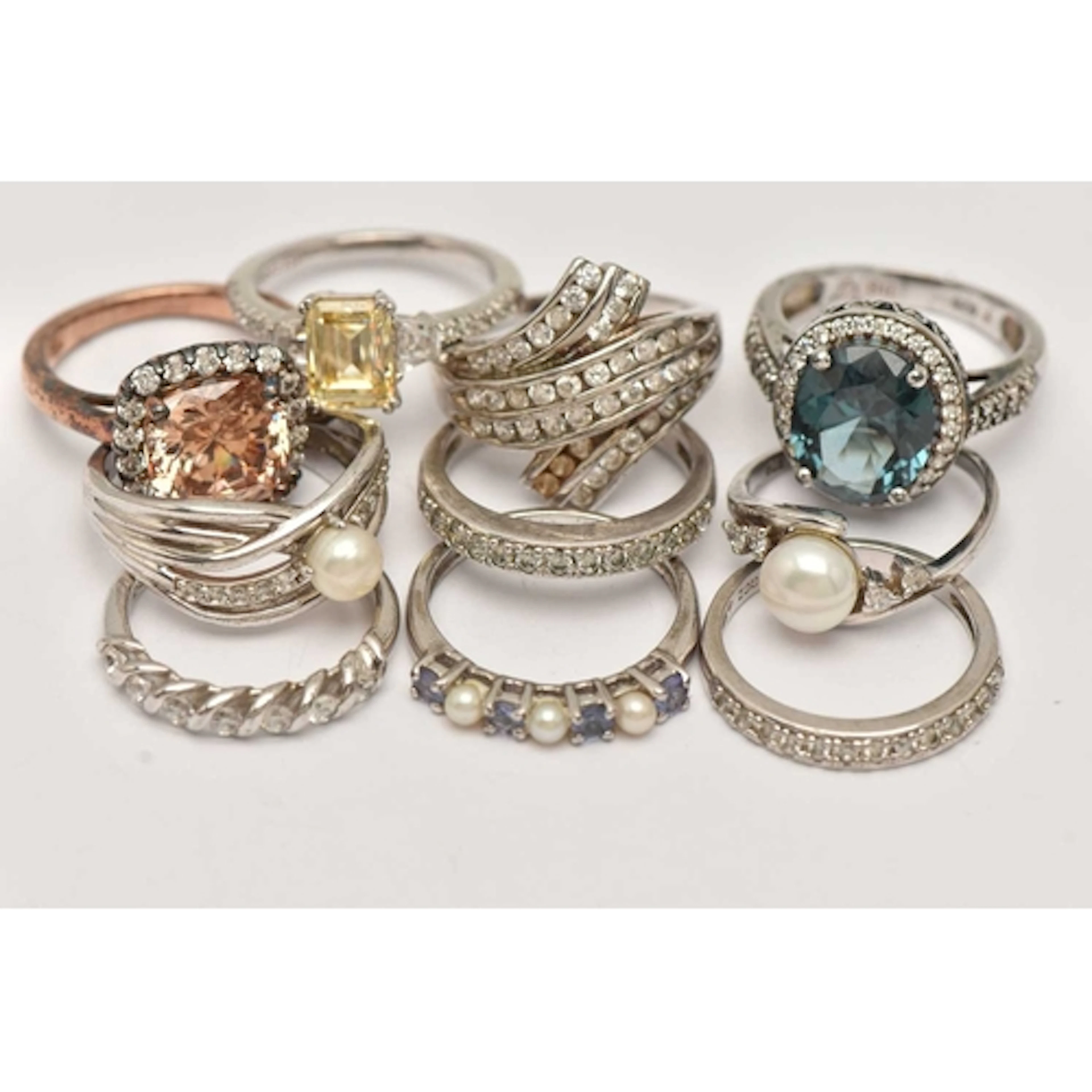 TEN WHITE METAL RINGS, various designs some set with culture...