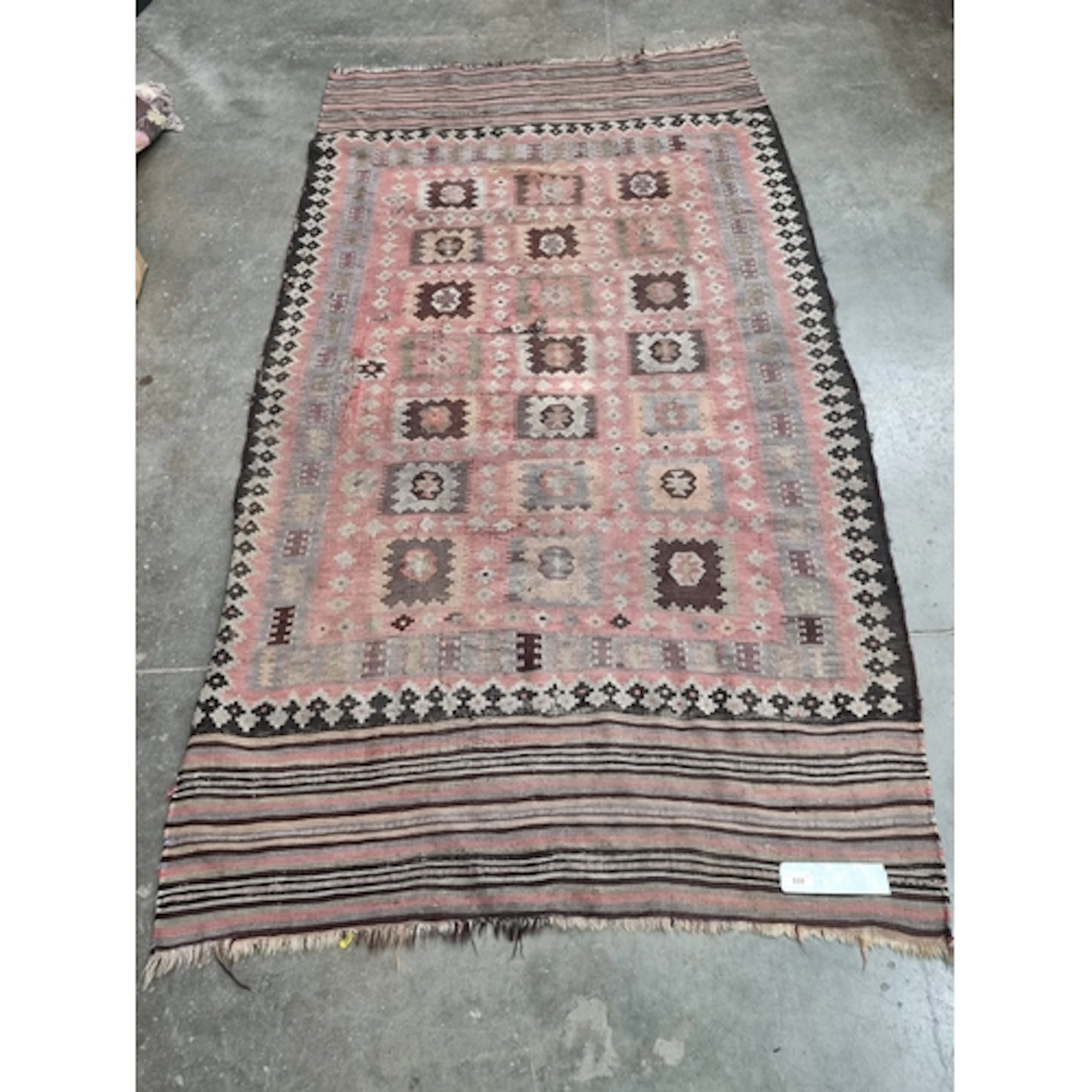 A Kelim Rug with stylised geometric designs on a red ground,...