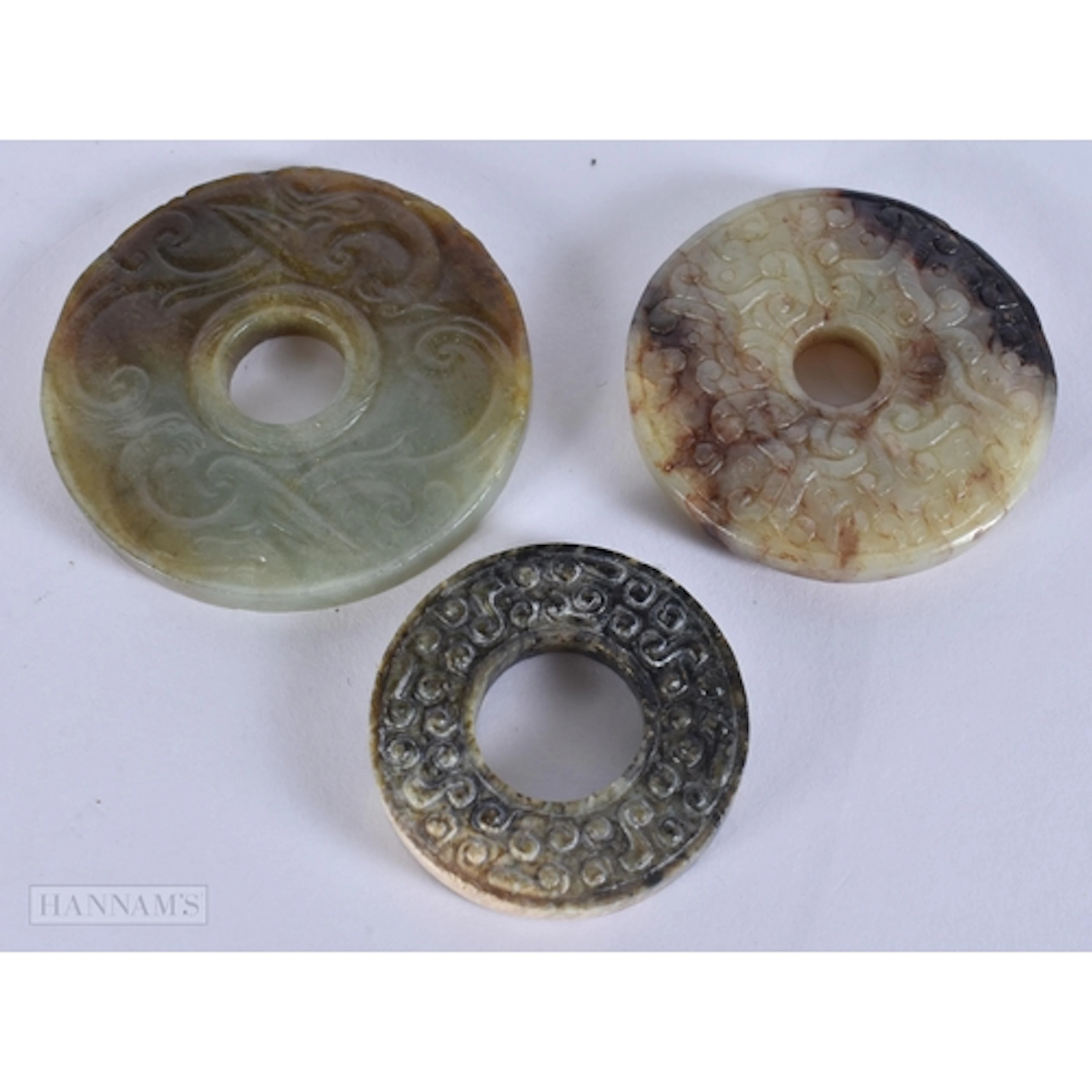 TWO EARLY CHINESE CARVED JADE BI DISCS together with another...