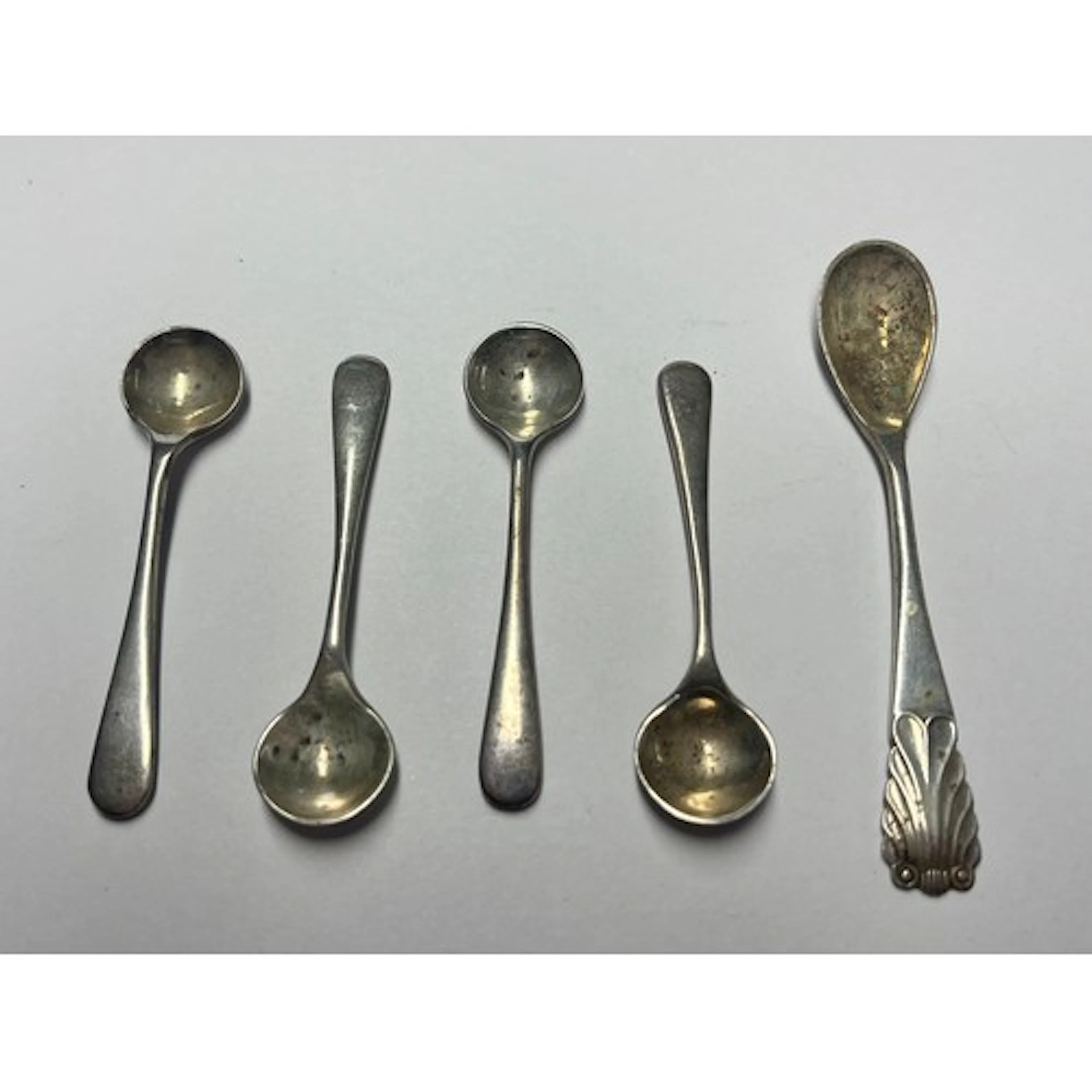 Four silver condiment spoons, with another, silver weight.