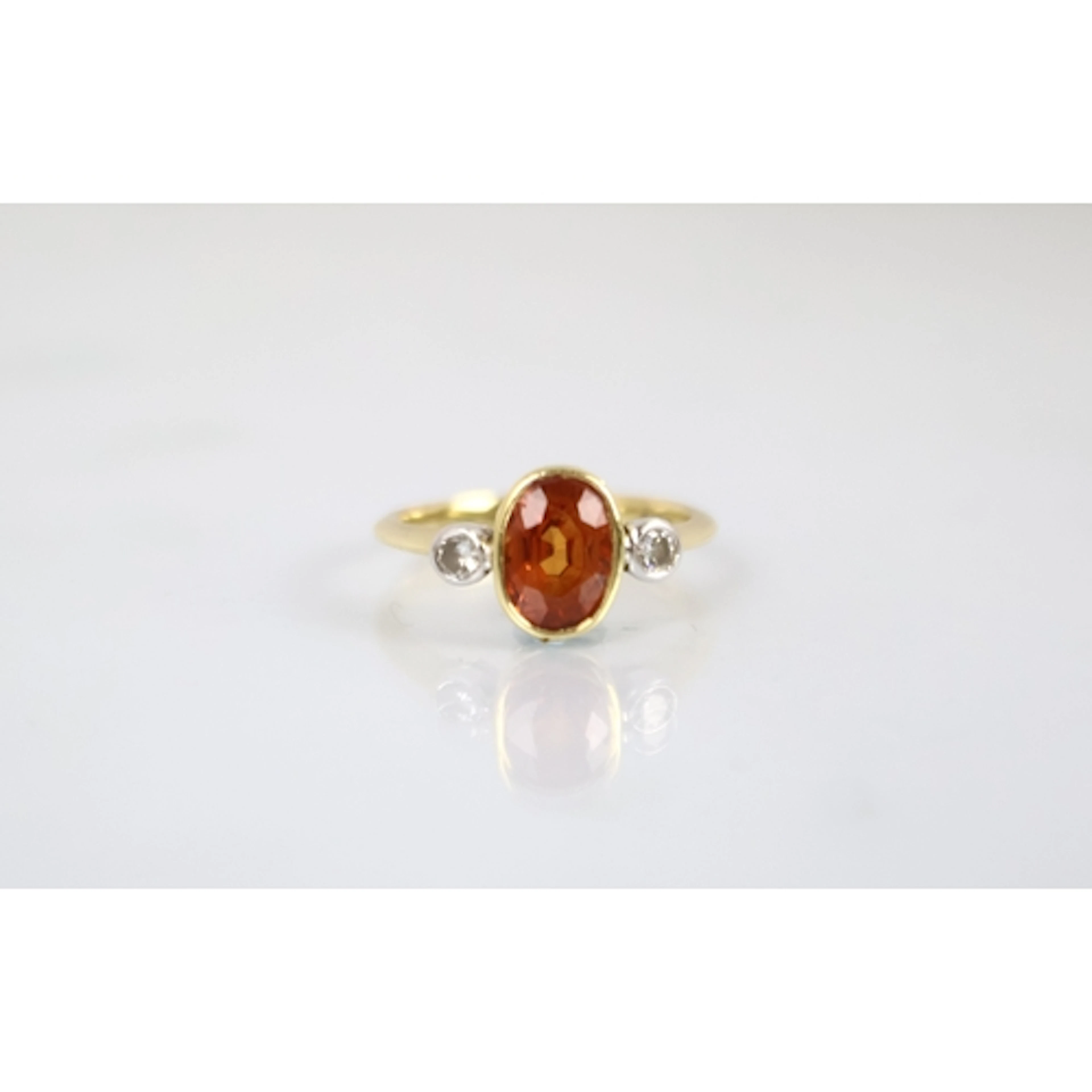 An orange padparadscha sapphire and diamond three stone ring...