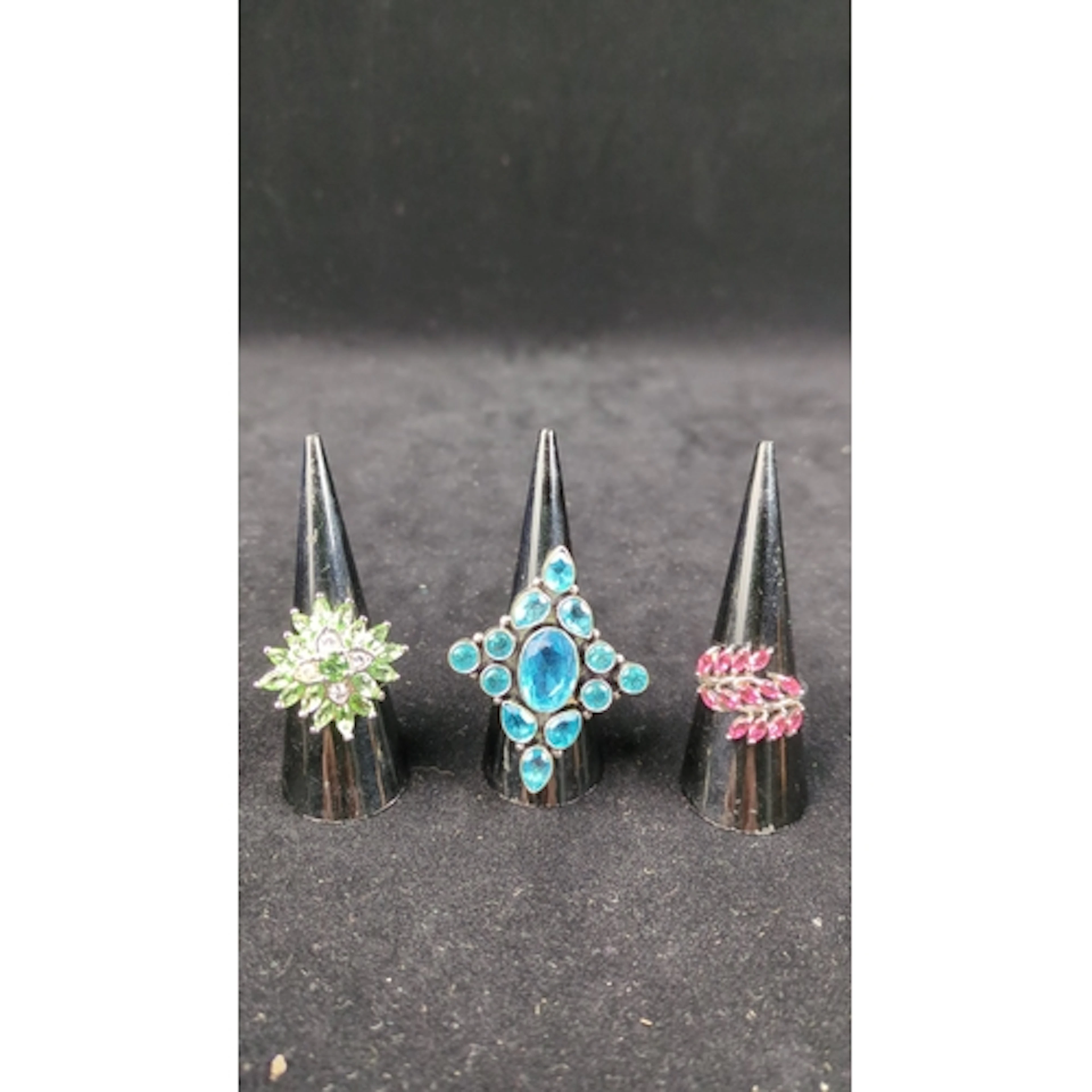 Three silver dress rings: one with a green floral cluster, o...