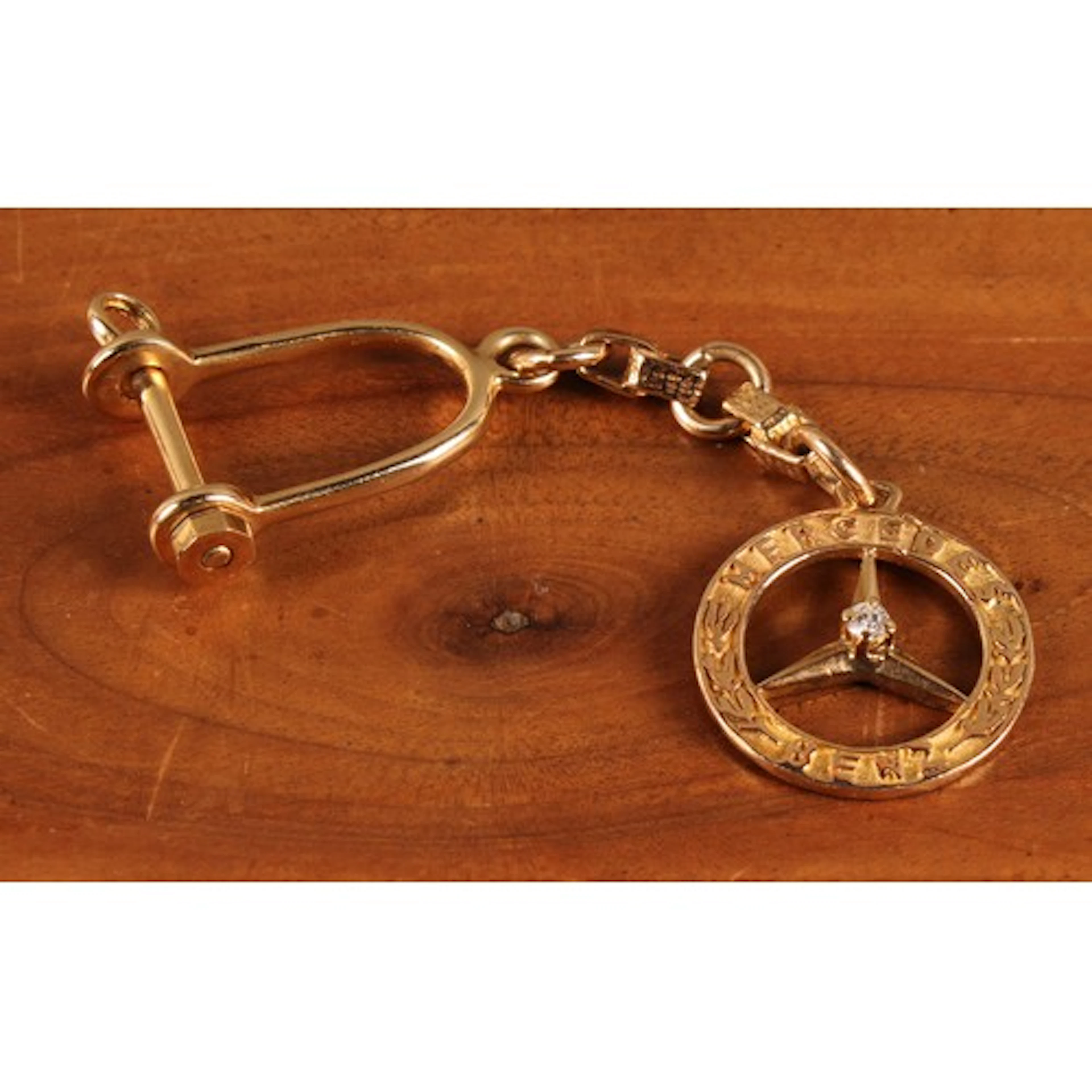 A gold coloured metal diamond set Mercedes Benz Logo keyring...