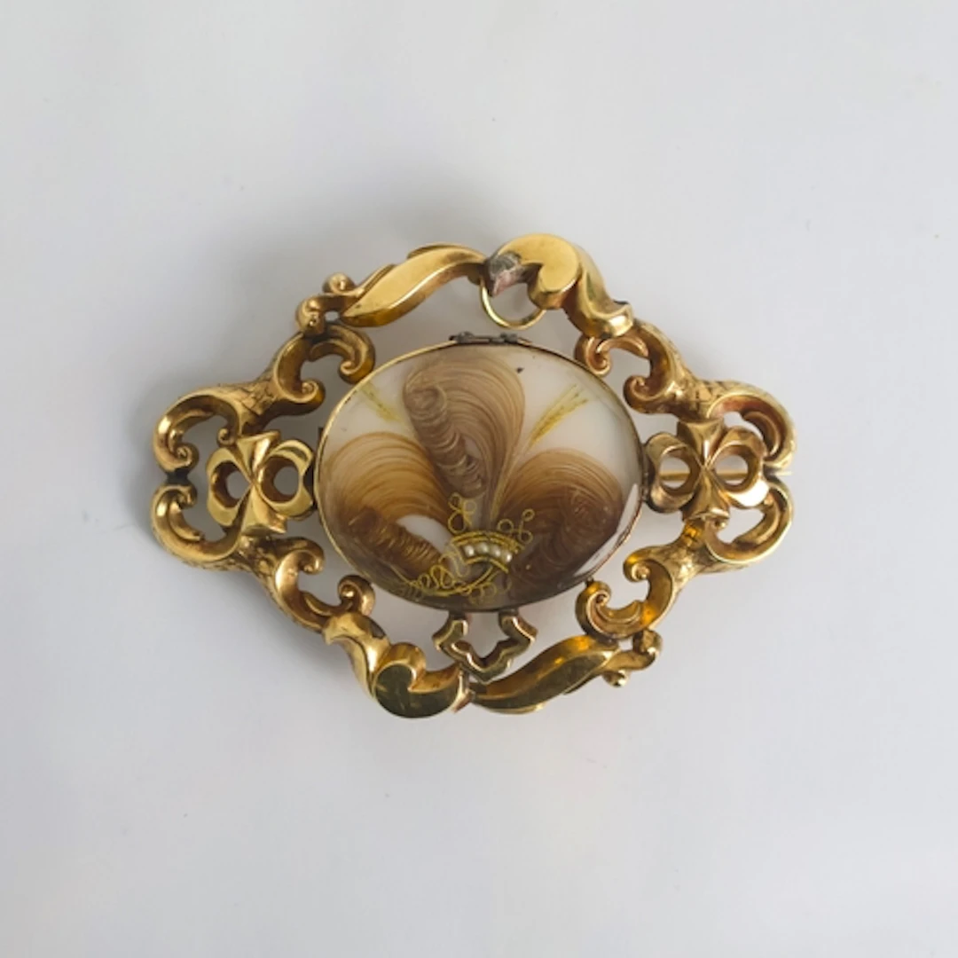 A 19th century mourning brooch, the glazed oval aperture wit...