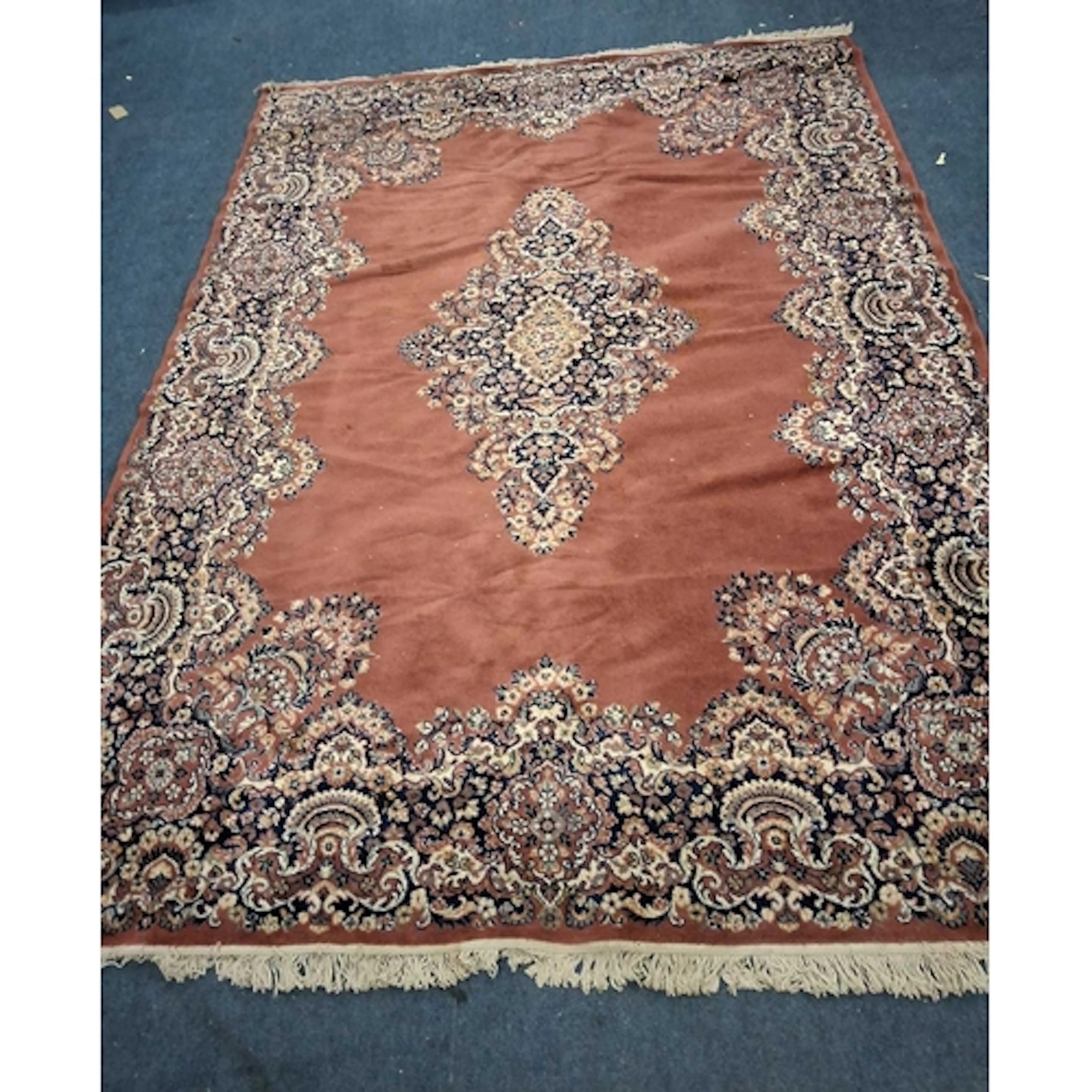 A RED GROUND RECTANGULAR WOOLLEN RUG, with repeating foliate...