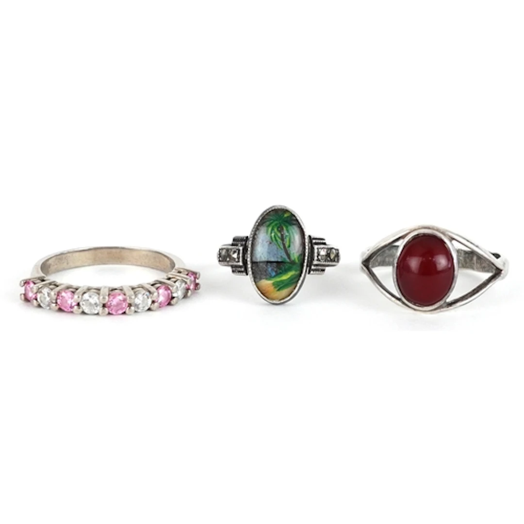 Three white metal rings, two set with colourful stones and a...