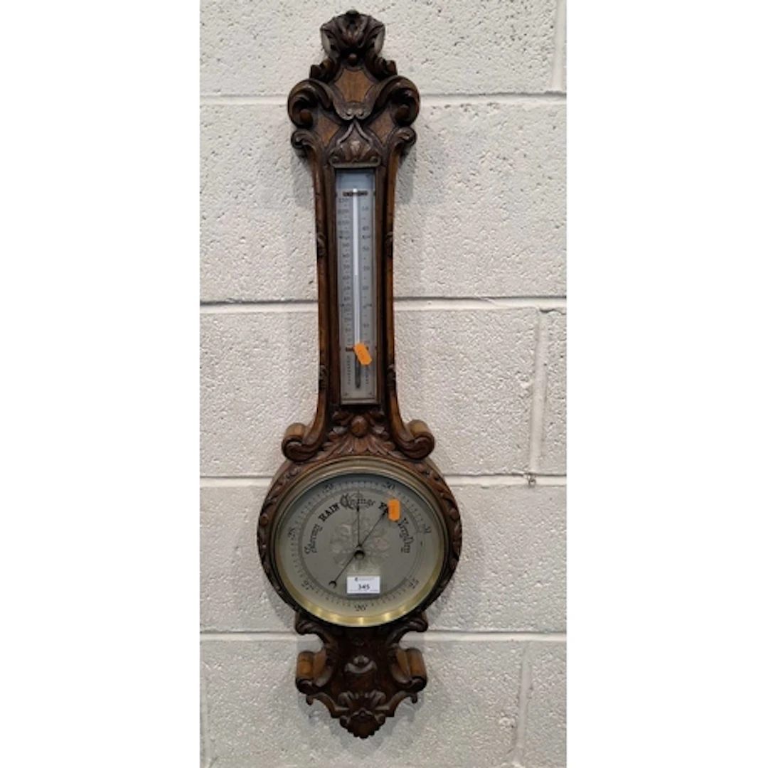 AN EARLY 20TH CENTURY OAK BAROMETER, with scrolled and folia...