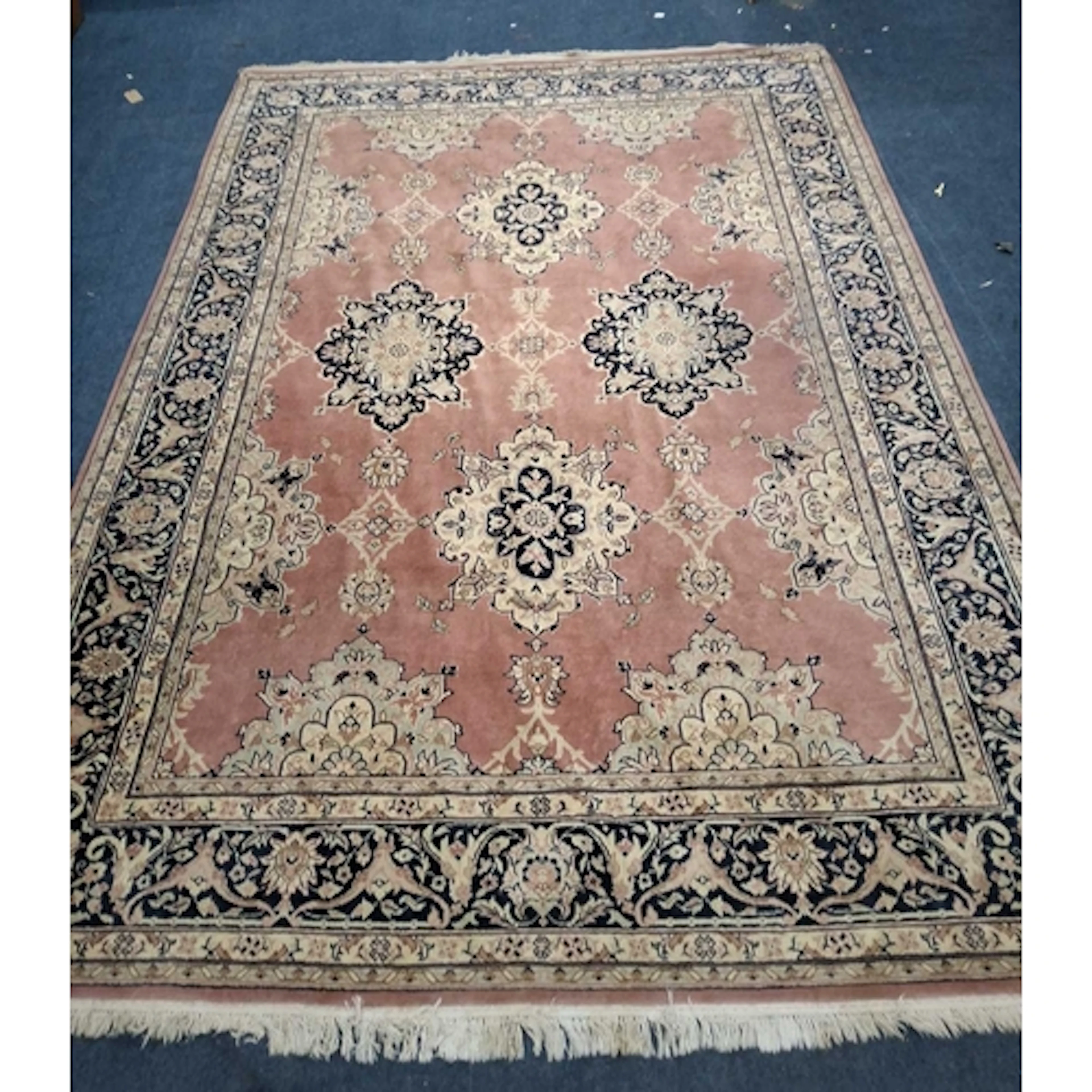 A LARGE PINK GROUND RECTANGULAR WOOLLEN RUG, with scrolled a...