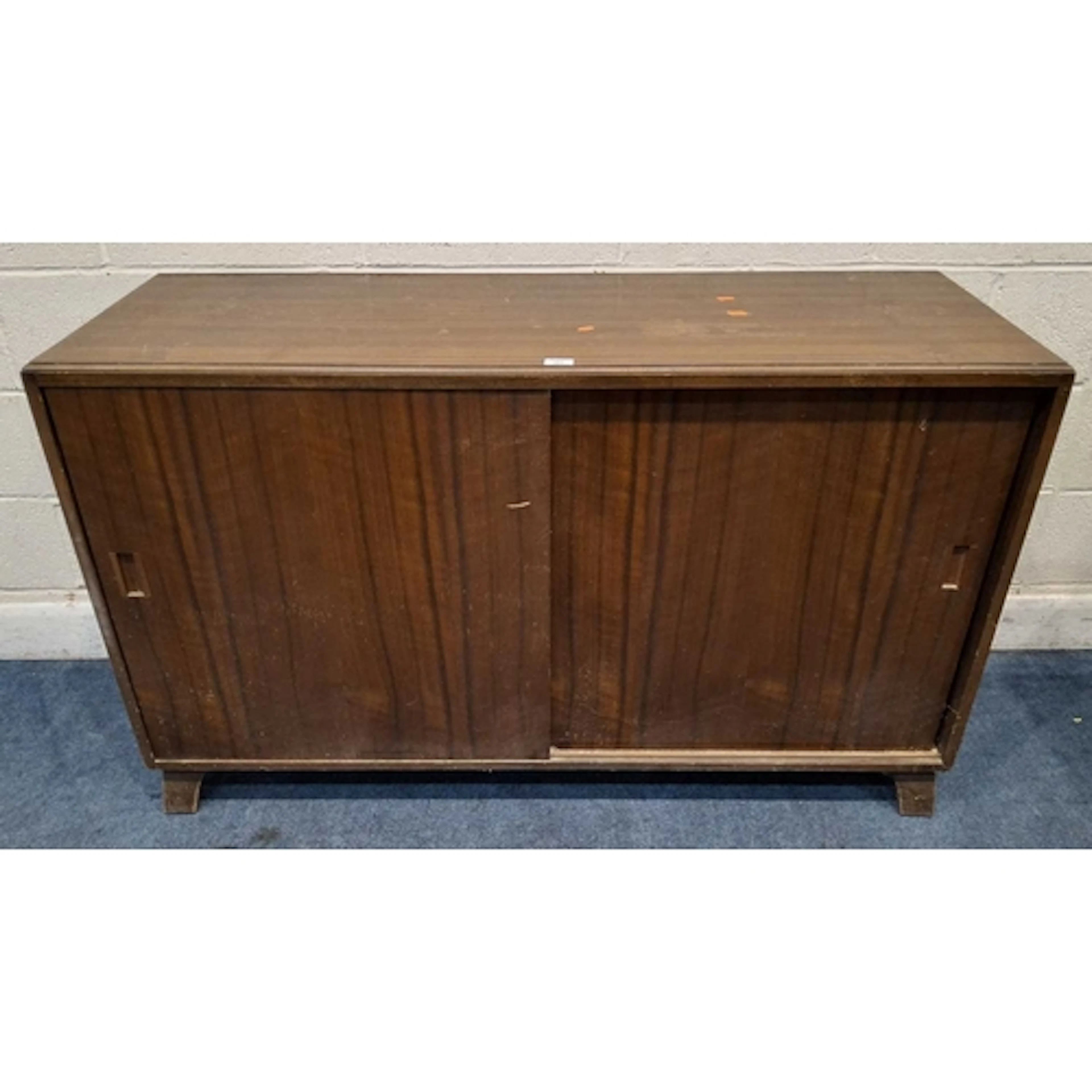 A MID-CENTURY TEAK CABINET, the double sliding cupboard door...