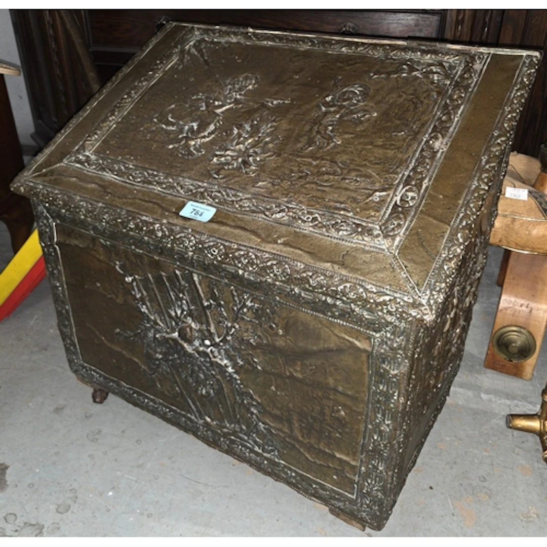 A 19th century embossed brass log box with sloped top on cas...