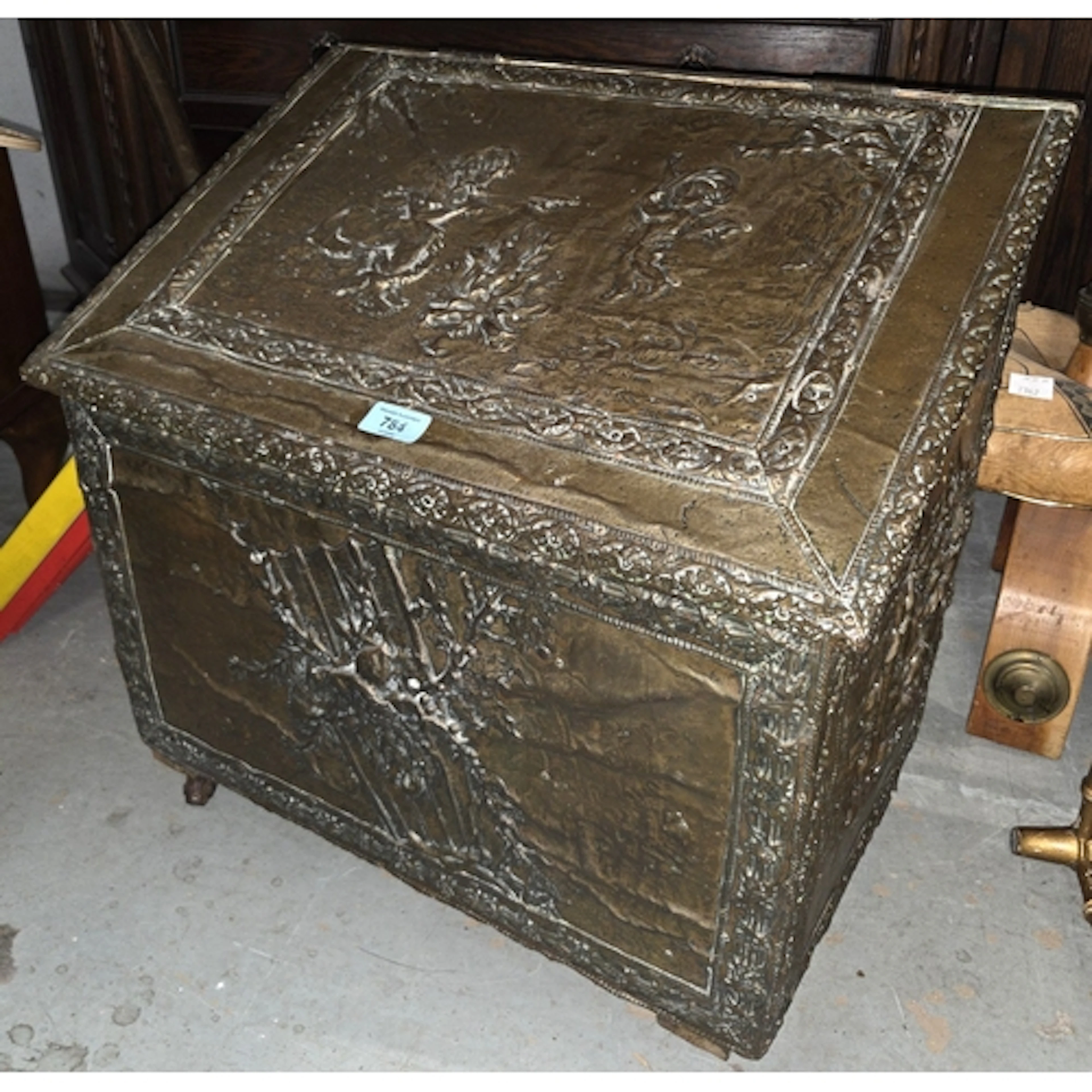 A 19th century embossed brass log box with sloped top on cas...