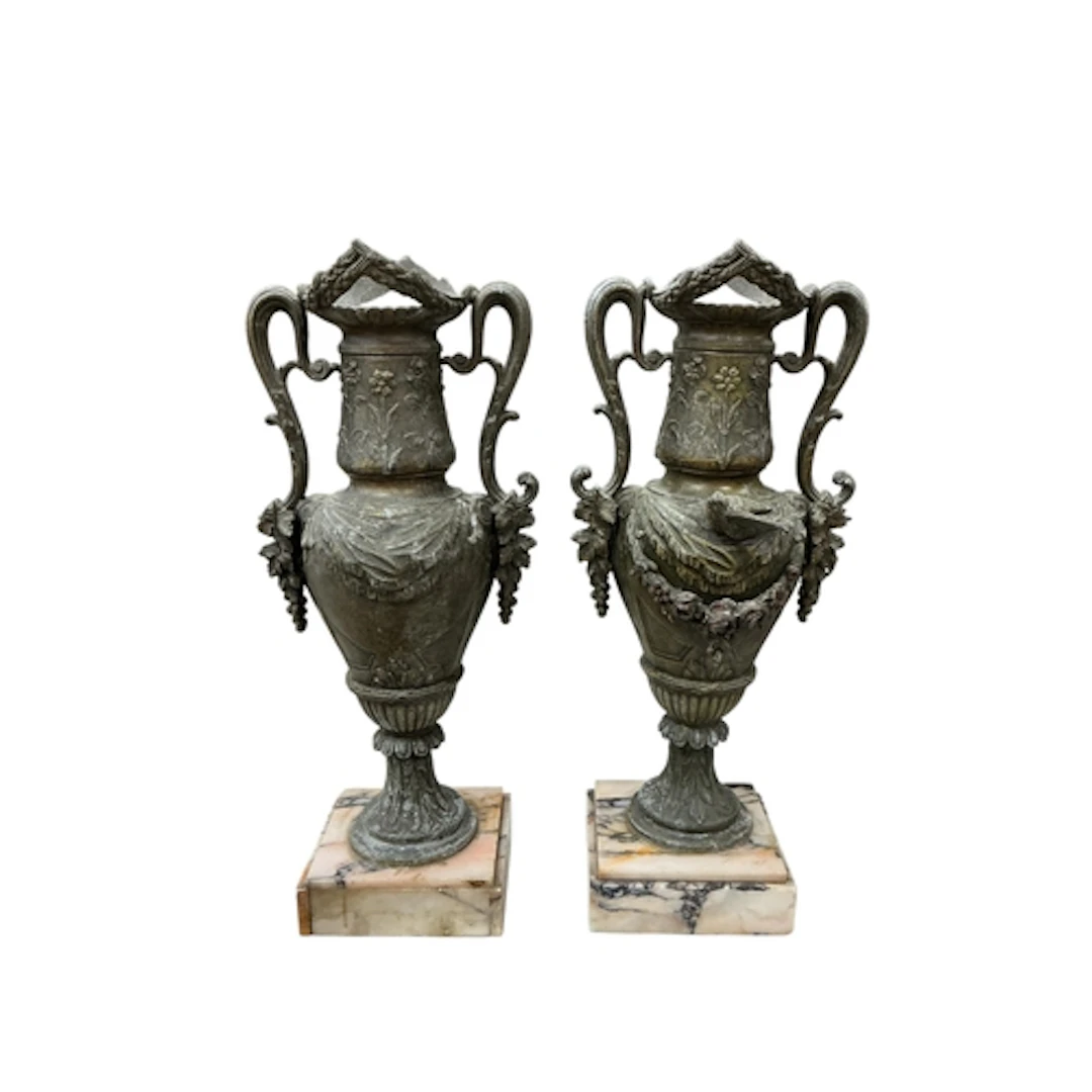 A pair of spelter twin handled urns raised on marble bases, ...