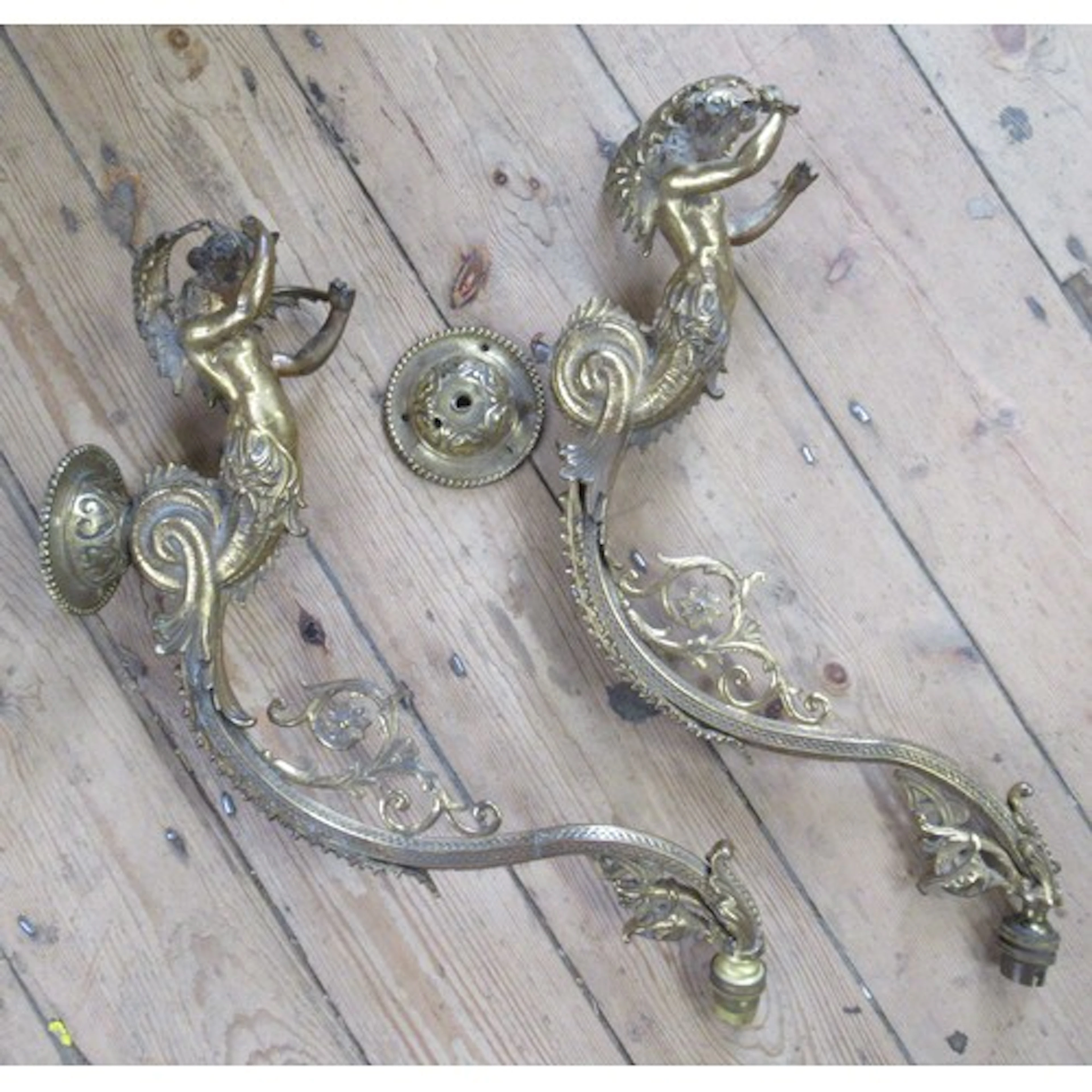 A pair of gilt metal ornate wall lights, formed as a Triton,...