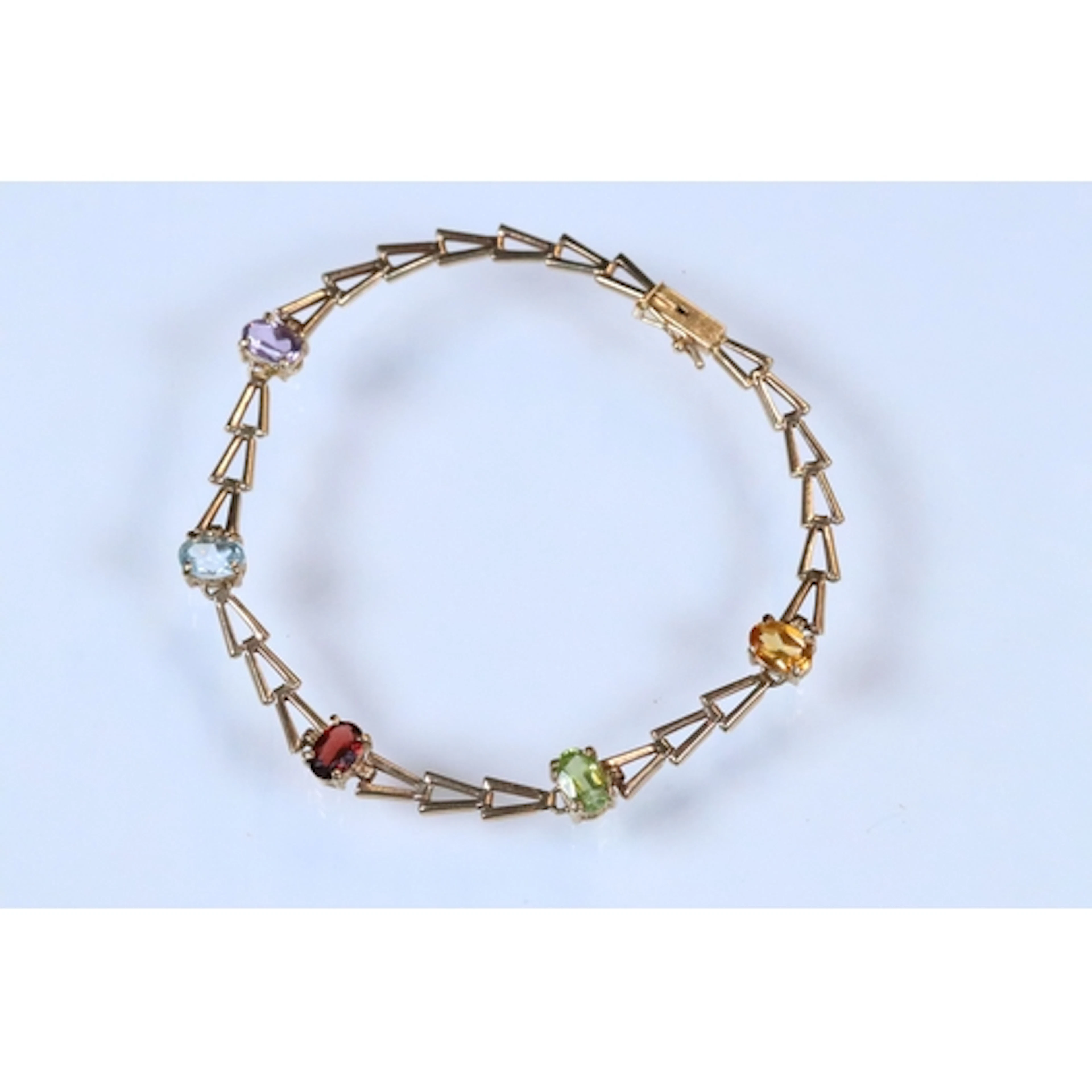Yellow metal and gemstome set bracelet. The bracelet having ...
