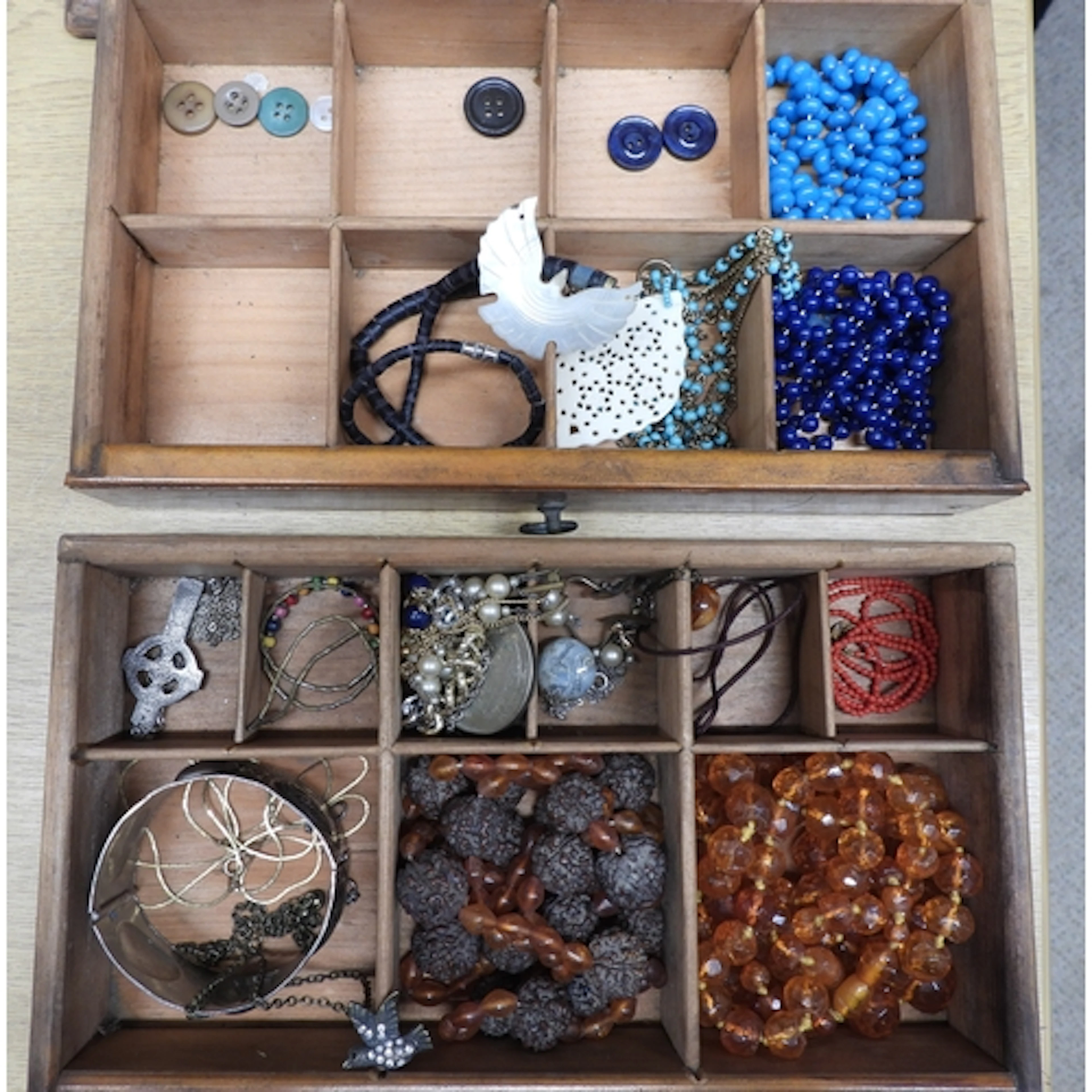 A wooden five drawer cabinet, full of beads, a mother of pea...