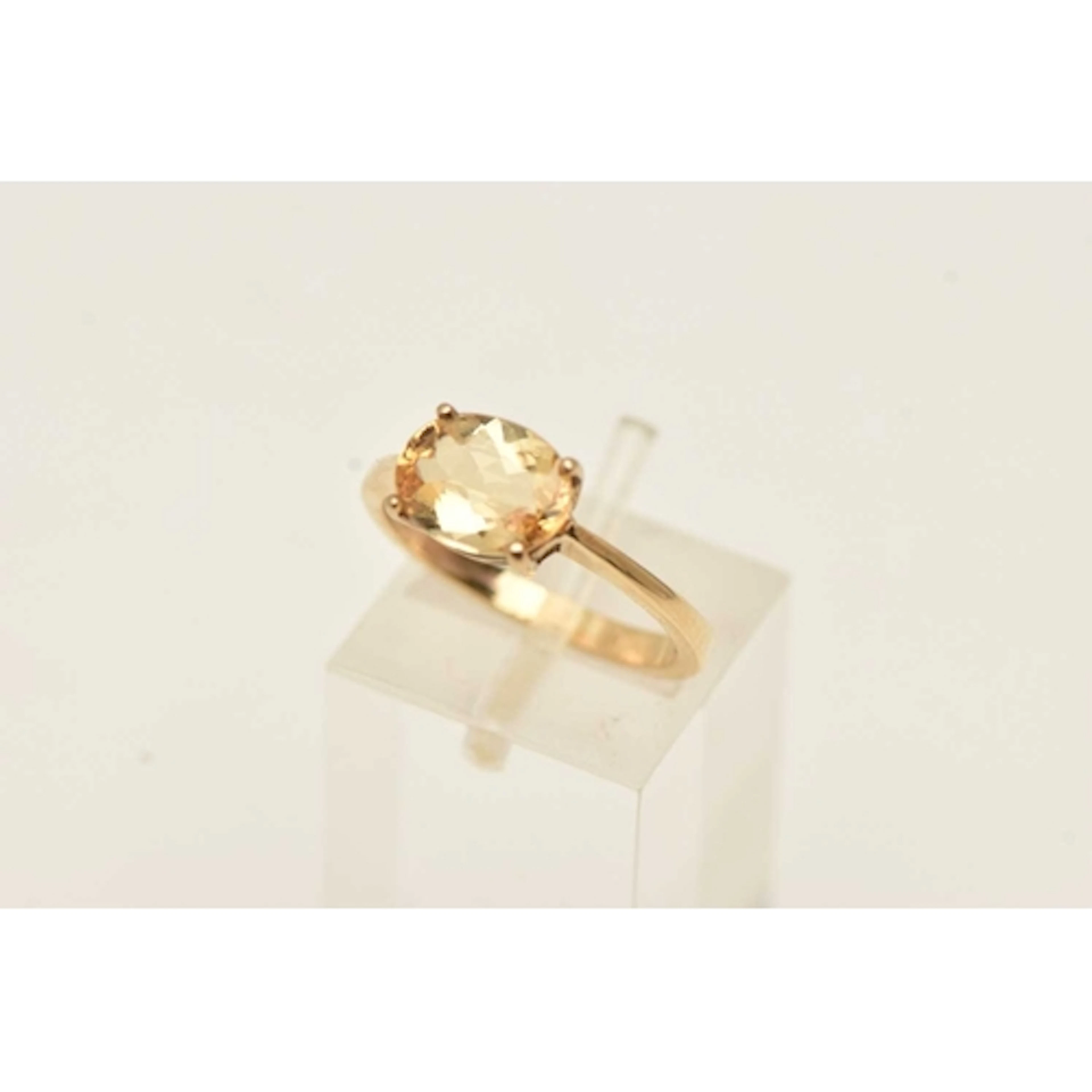A 9CT YELLOW GOLD GEM SET RING, an oval cut orange stone, as...