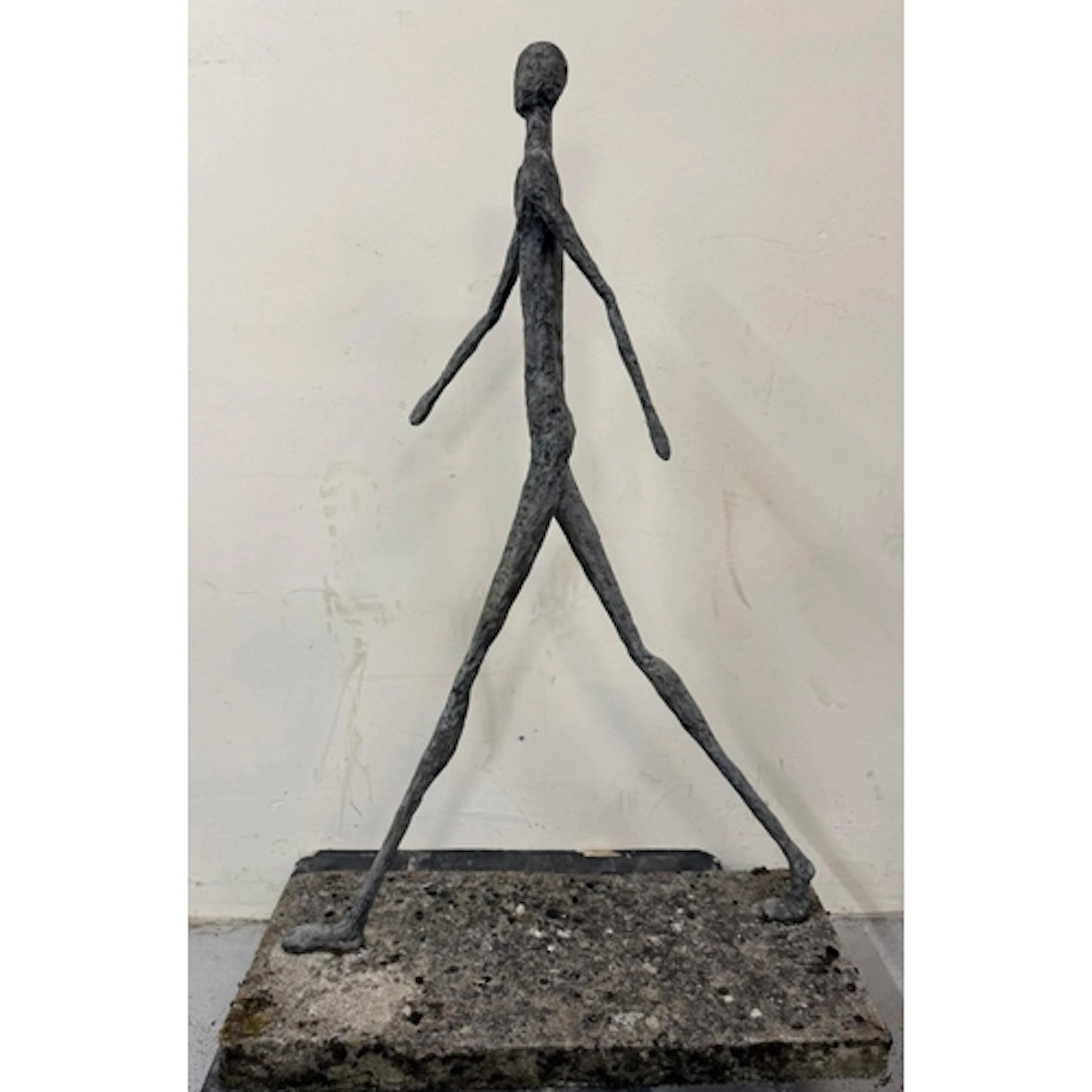 A slate resin sculpture of a walking man on concrete plinth ...