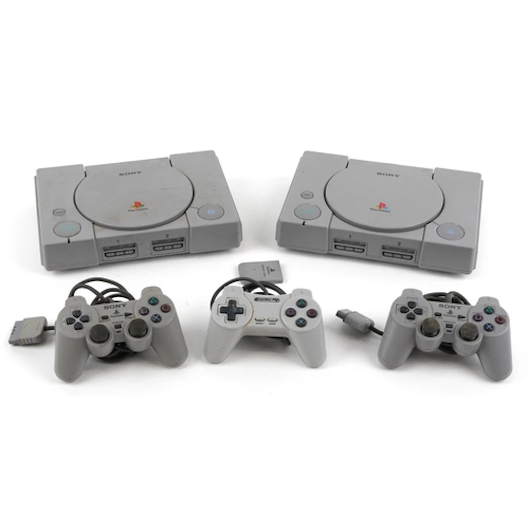 Two Sony PlayStation games consoles with three controllers.