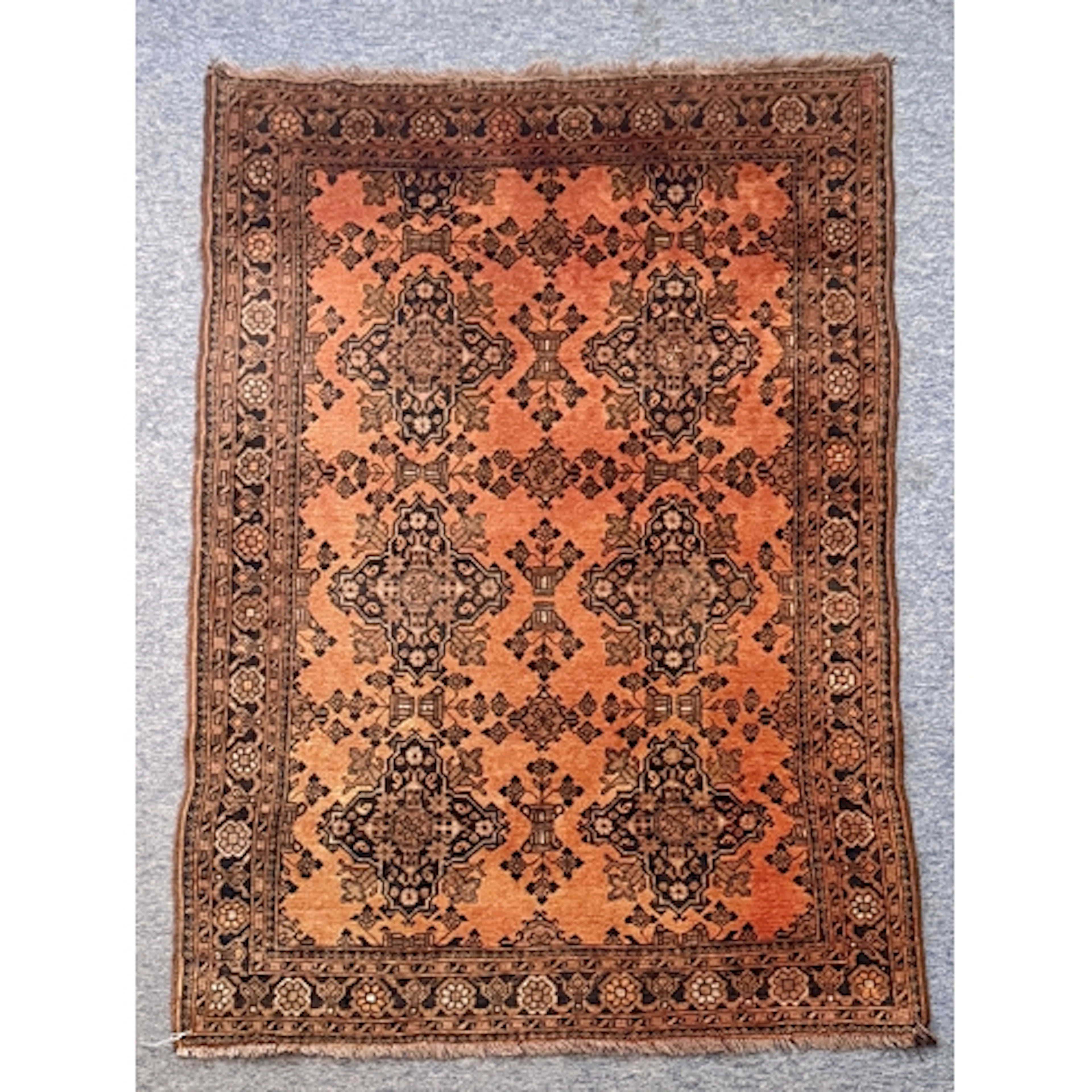 A hand knotted wool Turkmen rug - the pale madder field with...