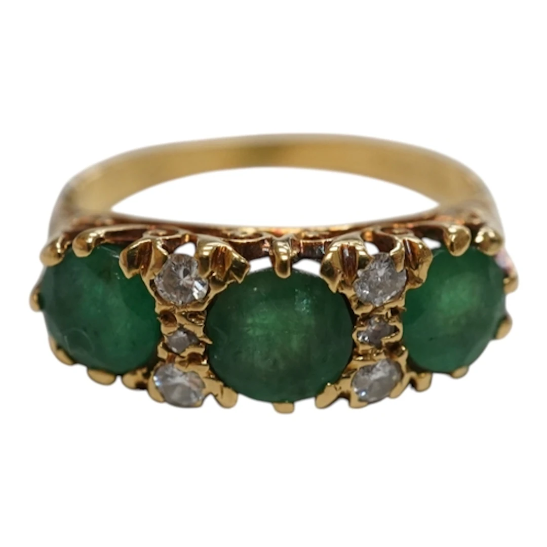 A recent 18ct gold and three stone emerald ring, with six st...