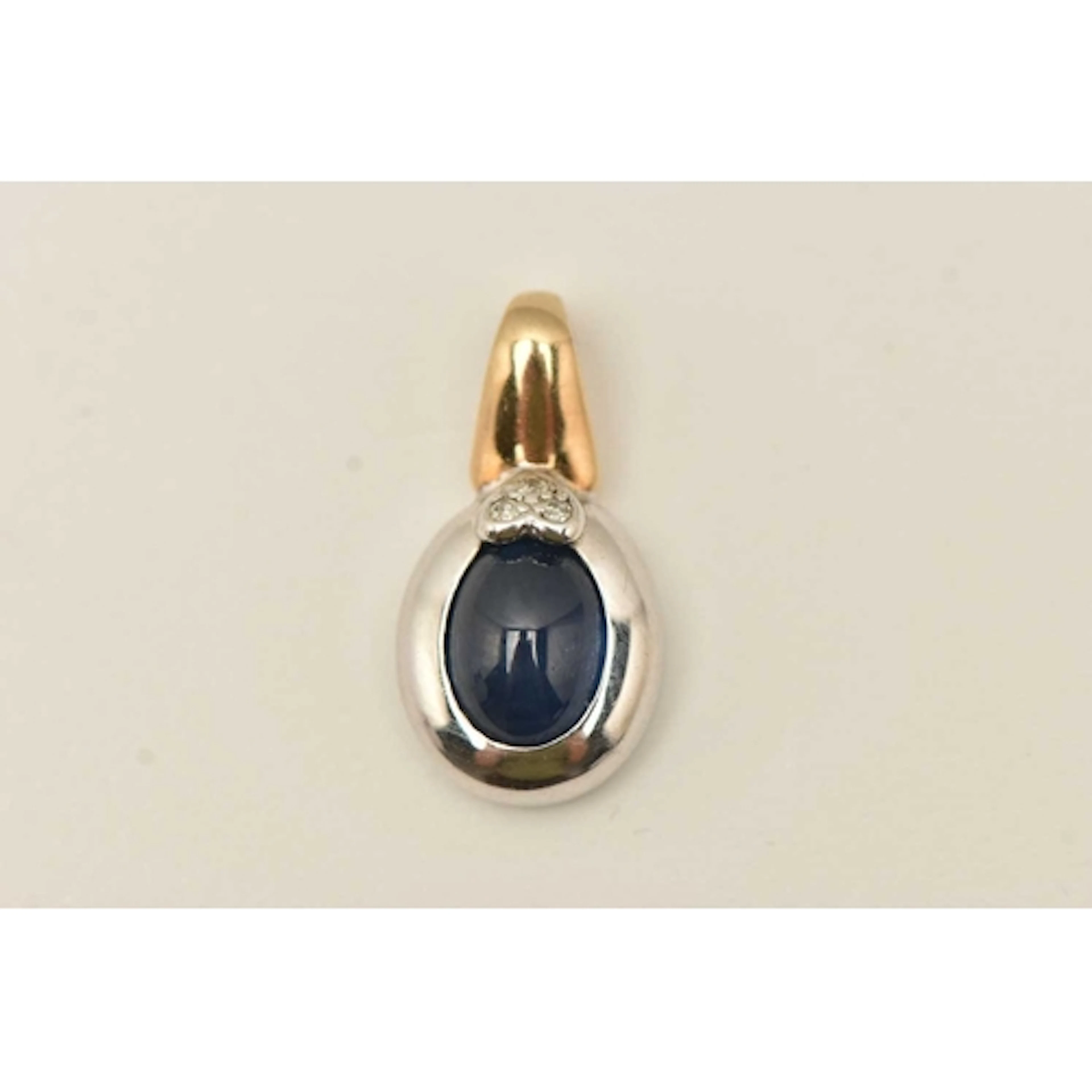 A 9CT BI COLOUR GEM SET PENDANT, an oval cabochon sapphire, ...