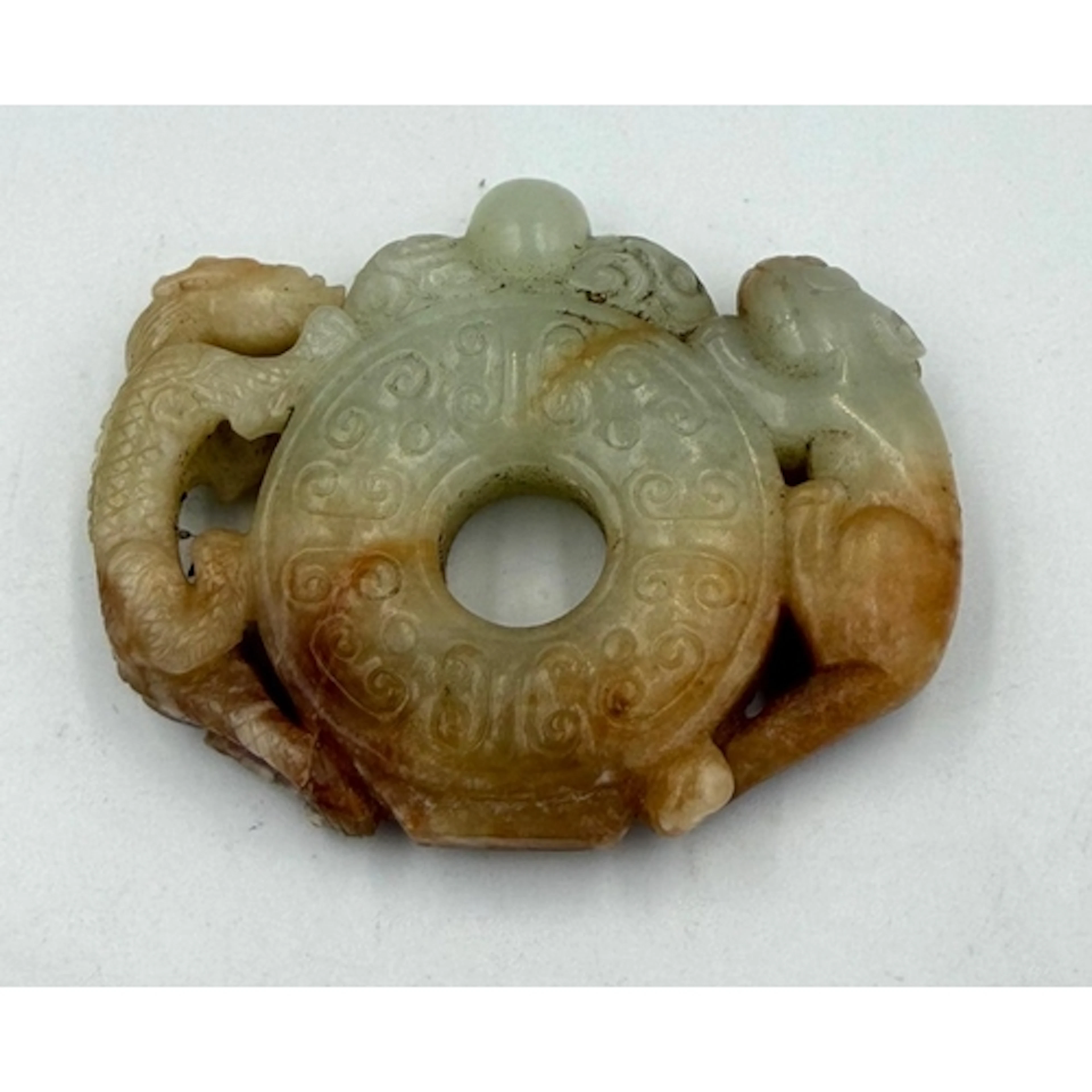 A Chinese jade disc pendant with mythical beast design. 70mm...