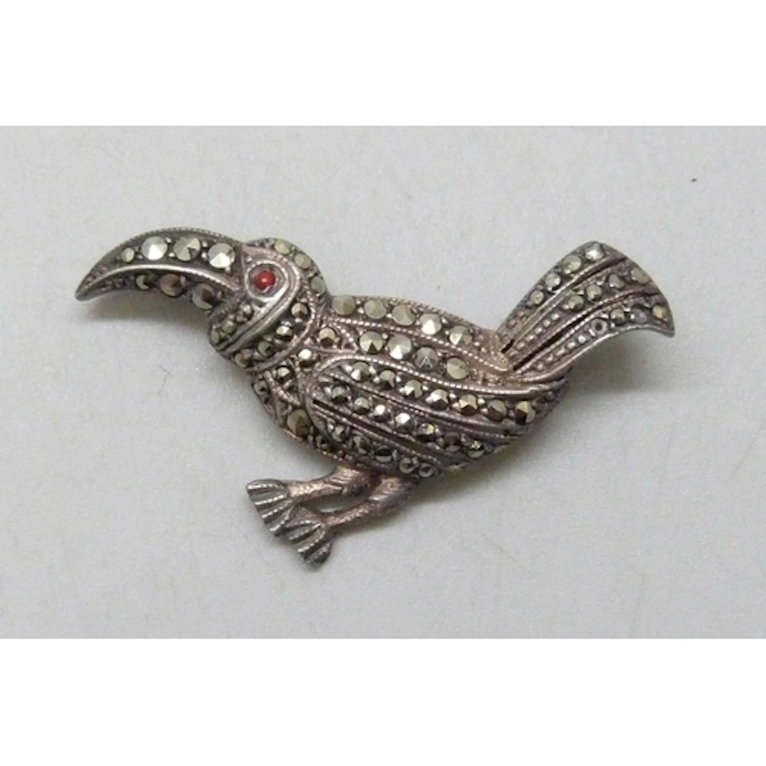 An Art Deco white metal, marcasite and possibly coral bird b...