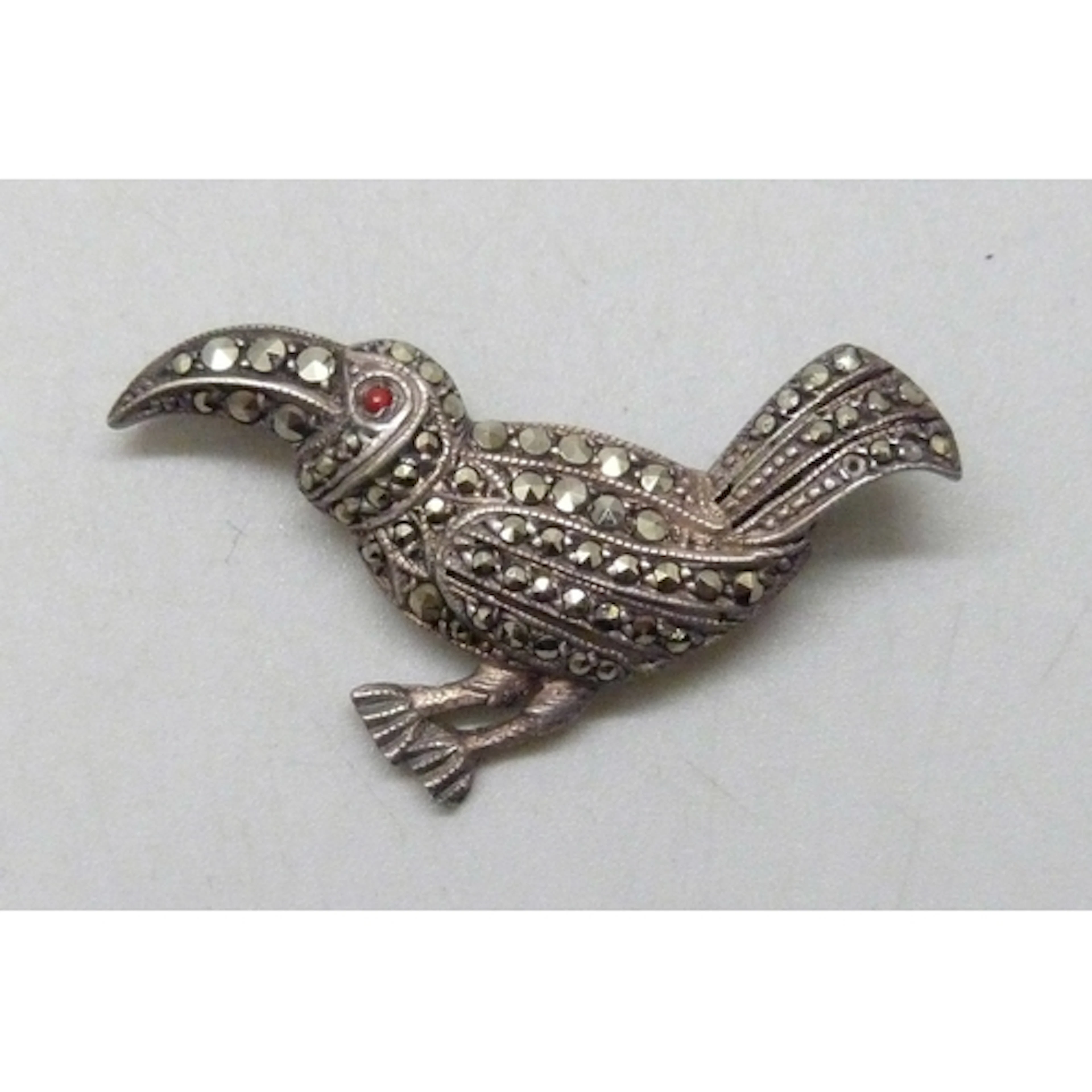 An Art Deco white metal, marcasite and possibly coral bird b...