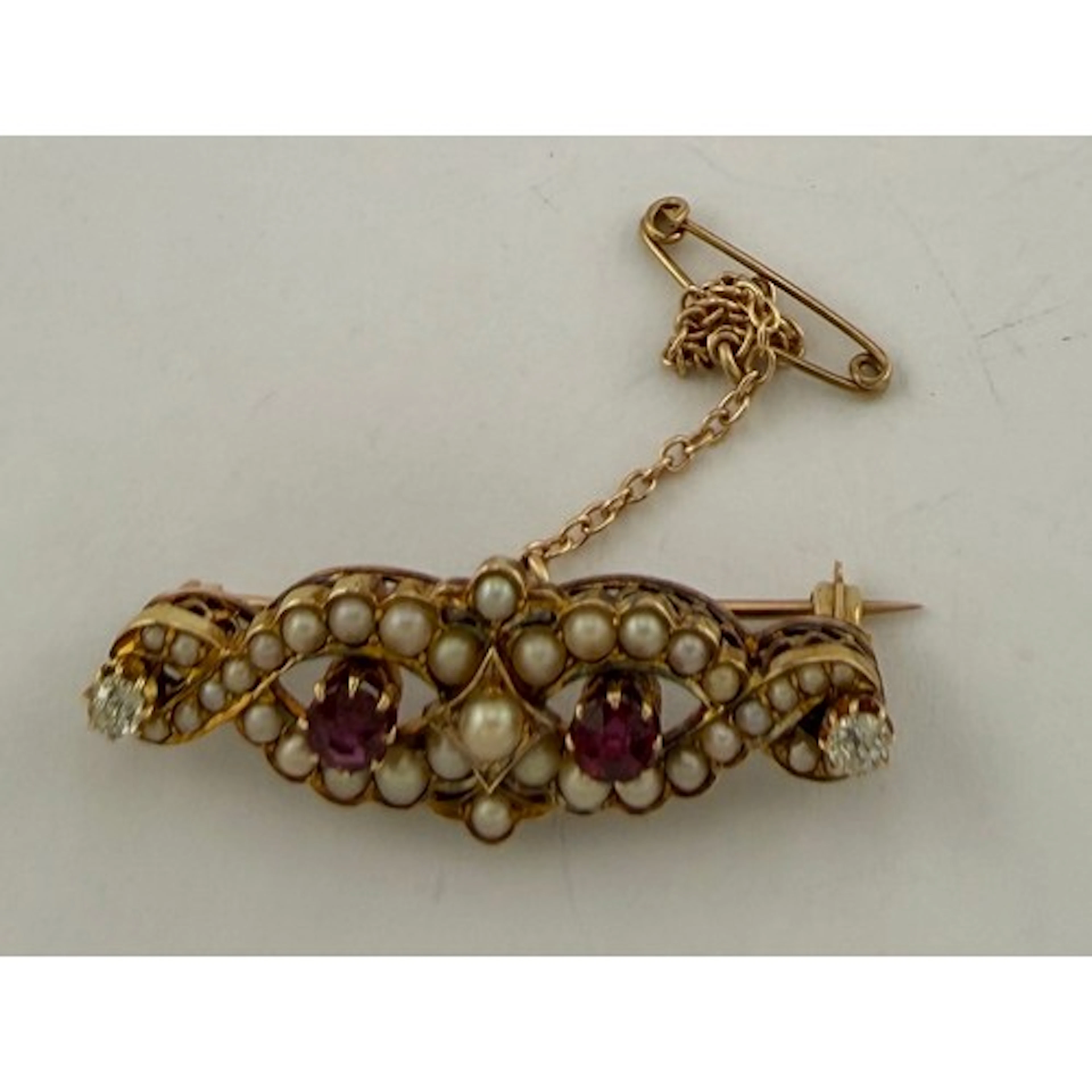 A yellow metal bar brooch set with rubies, diamonds and seed...