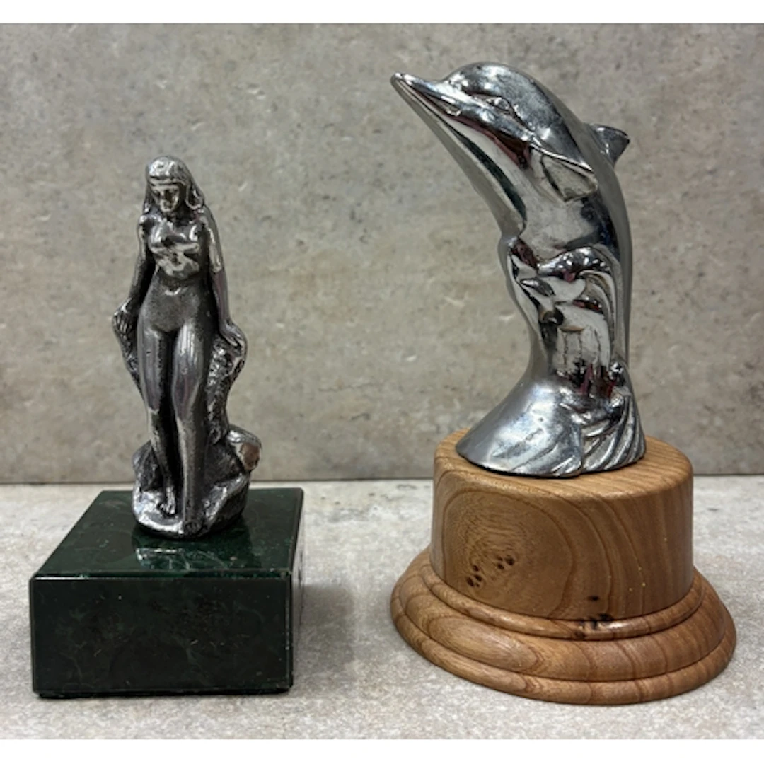 A bonnet mascot in the form of a leaping dolphin together wi...