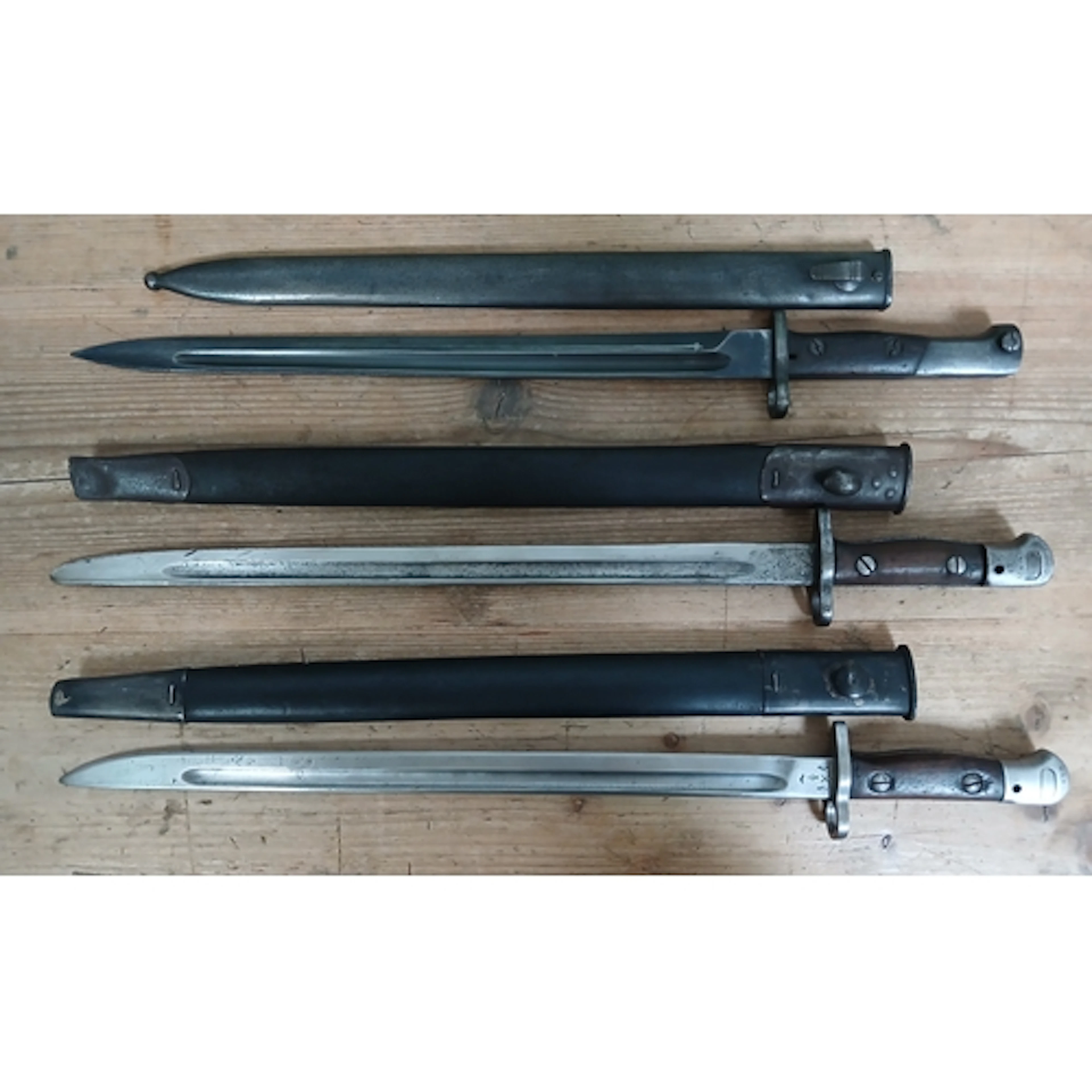A group of three 1907 Lee Enfield bayonets and scabbards.