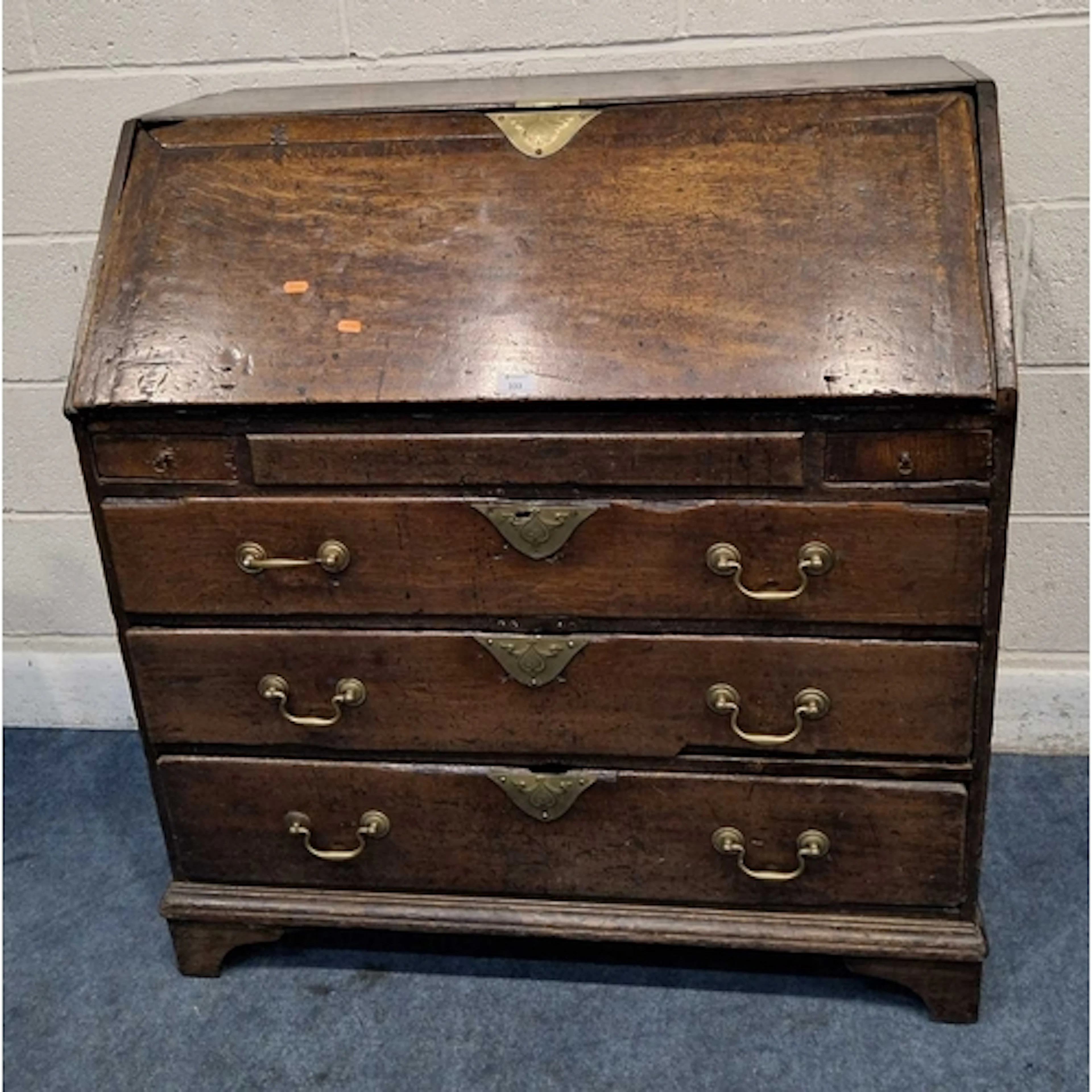A GEORGIAN OAK BUREAU, the fall front door enclosing a fitte...