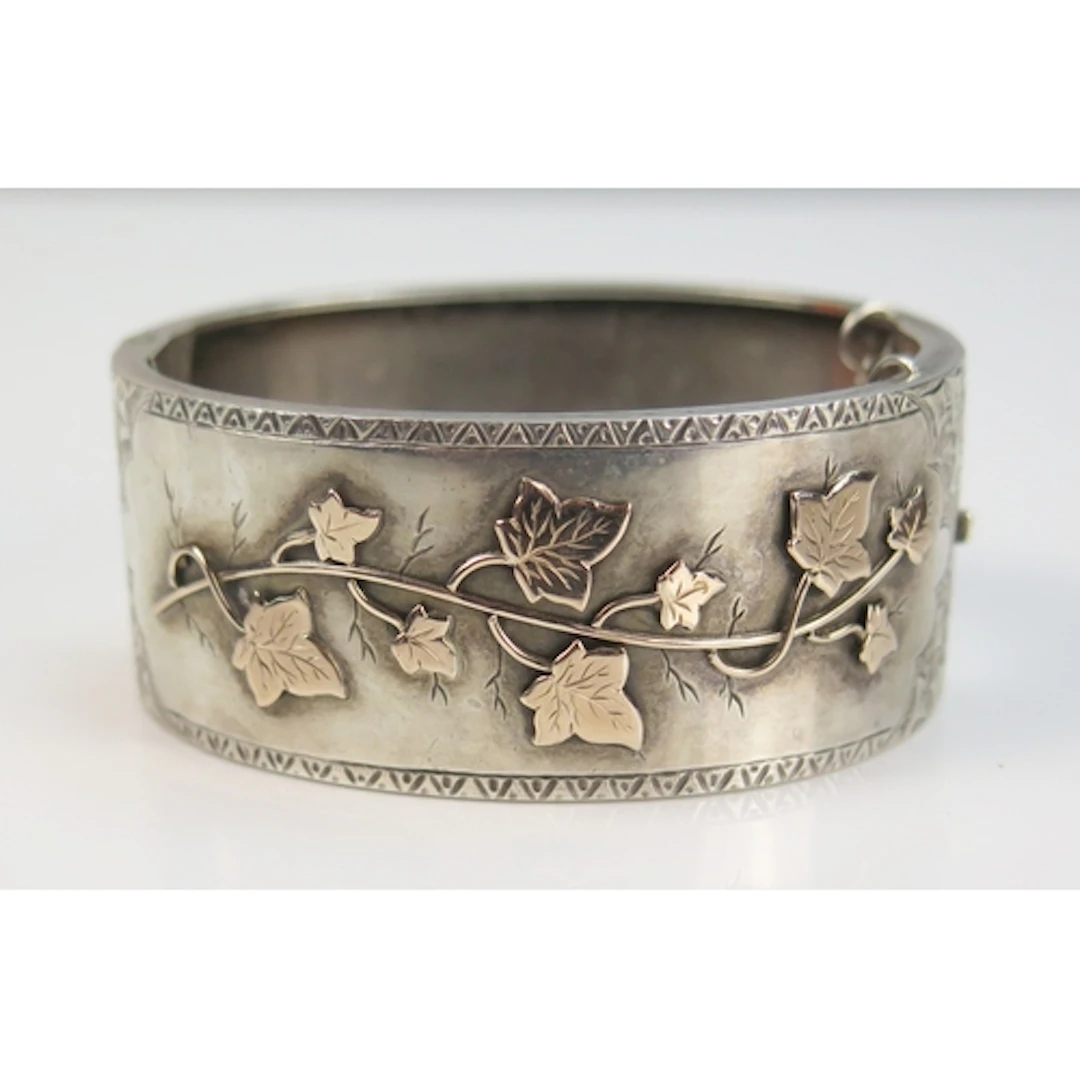 A silver hinged bangle with chased foliate decoration and pr...