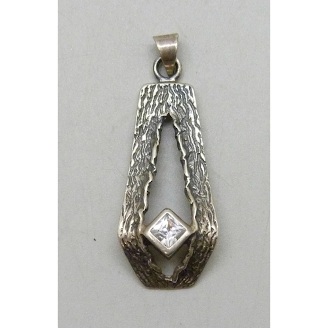 A Modernist/Brutalist design silver pendant set with a white...