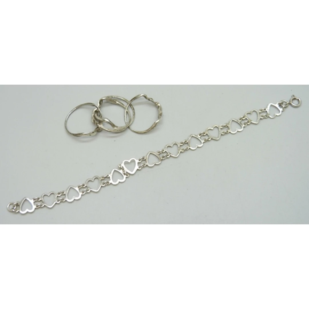 A white metal fretwork heart design bracelet, and a white me...