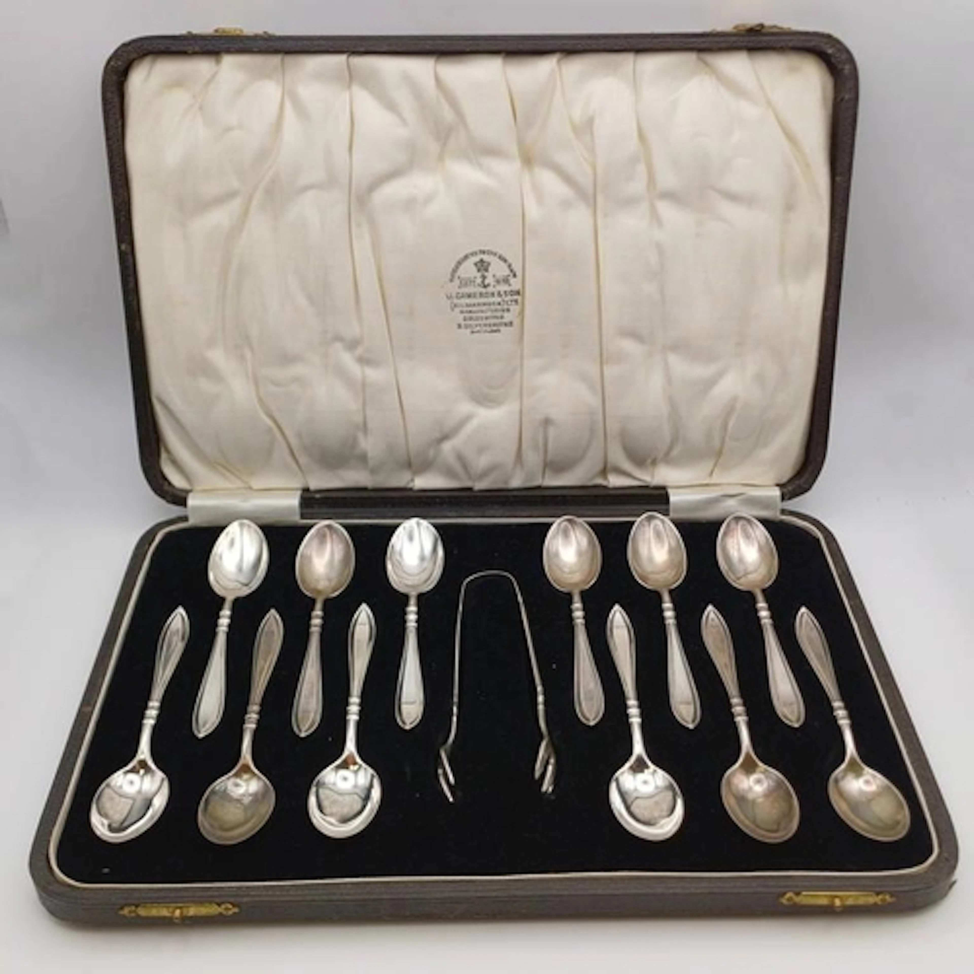 A CASED SET OF 12 SILVER TEASPOONS & SUGAR TONGS BY DOCKER &...