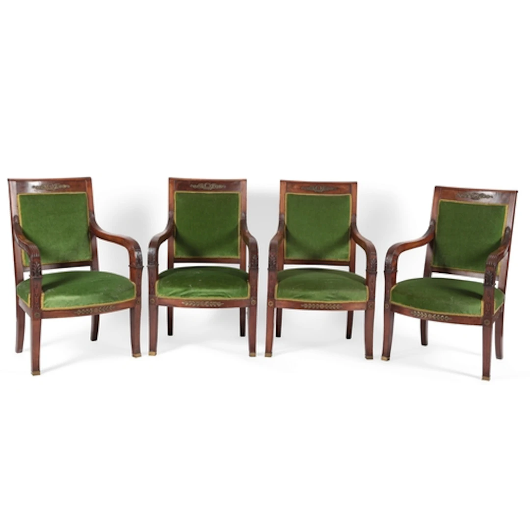 A set of four French Empire walnut fauteuils, each top rail ...