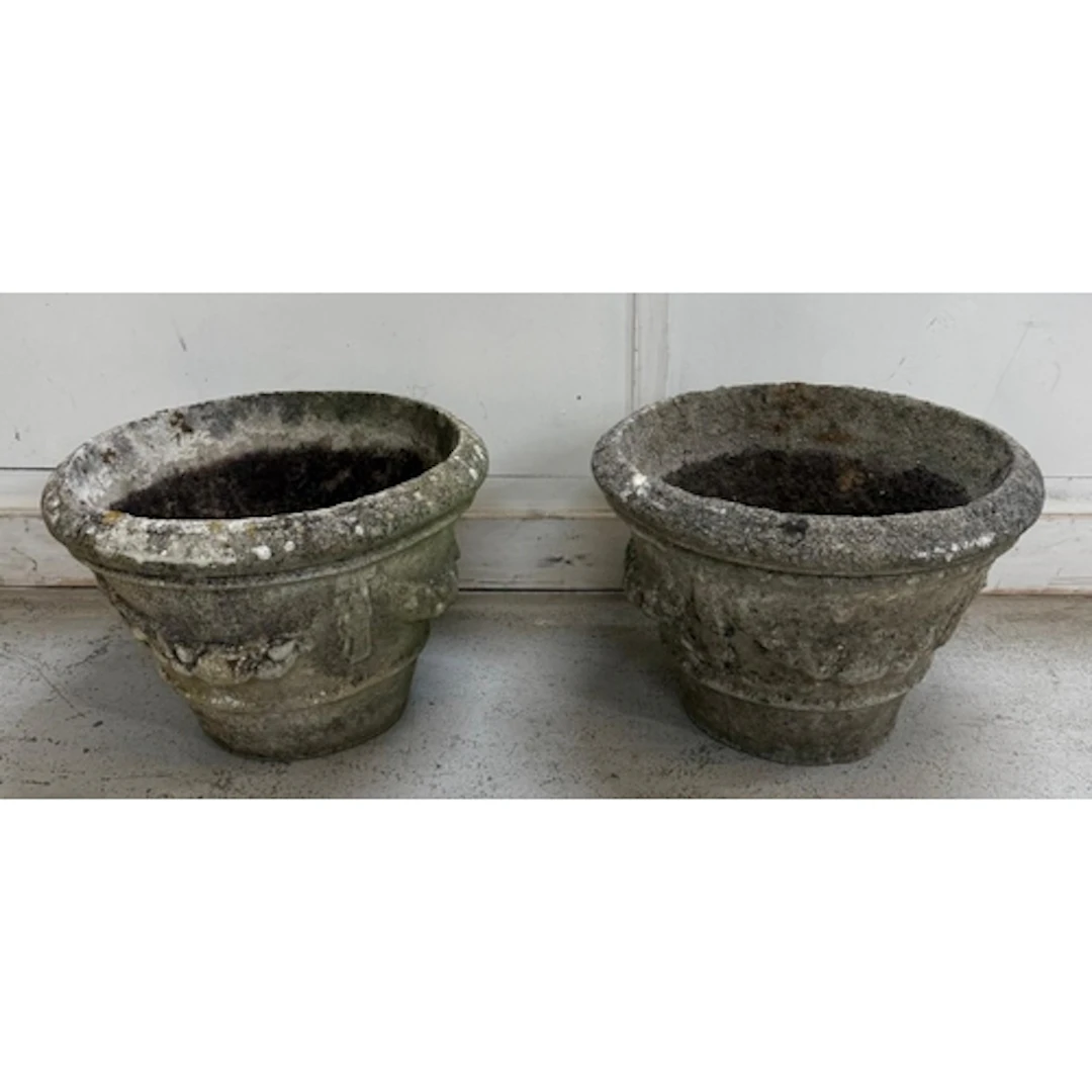 A pair of weathered concrete garden planters with swag relie...