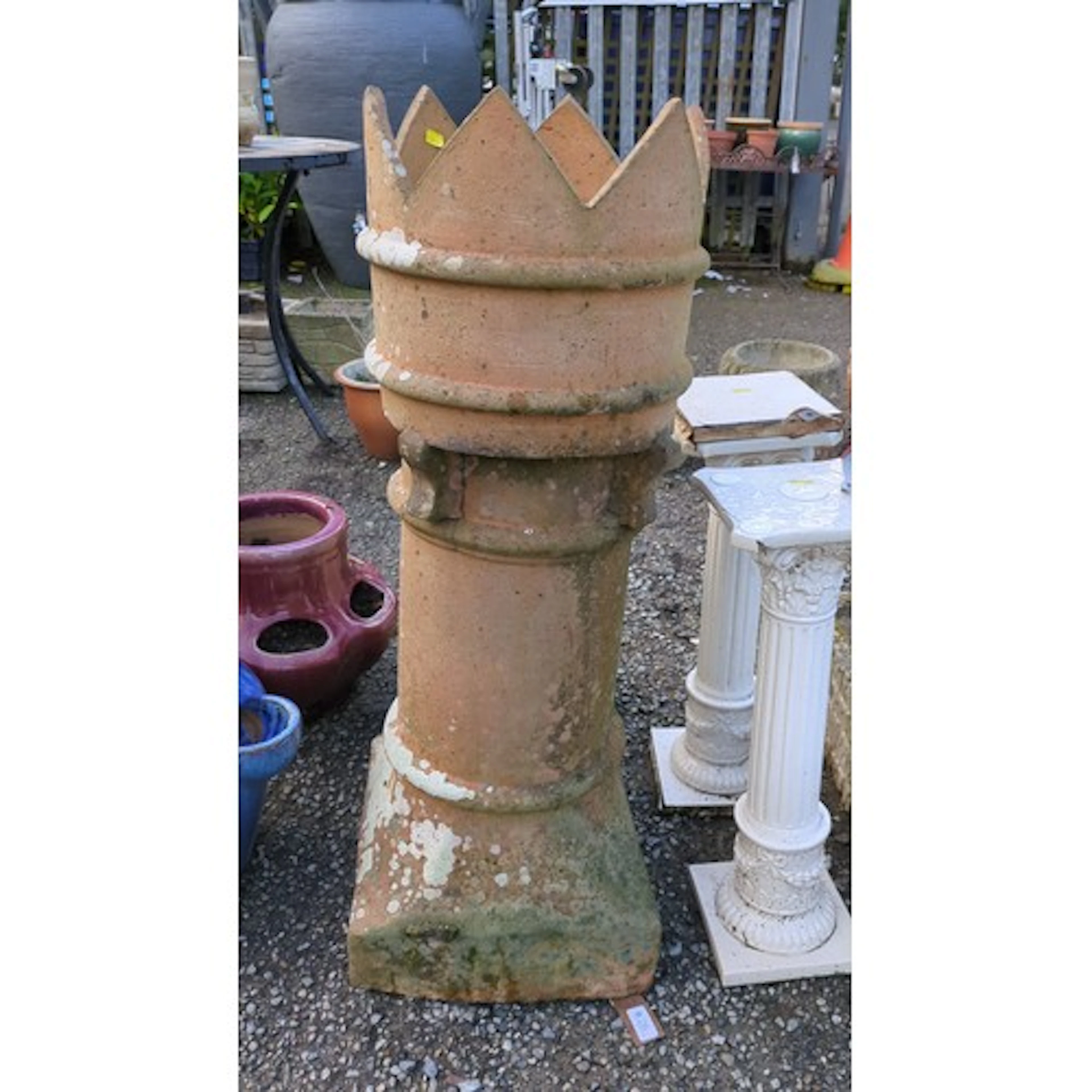 Terracotta chimney pot with crenelations above moulded bands...