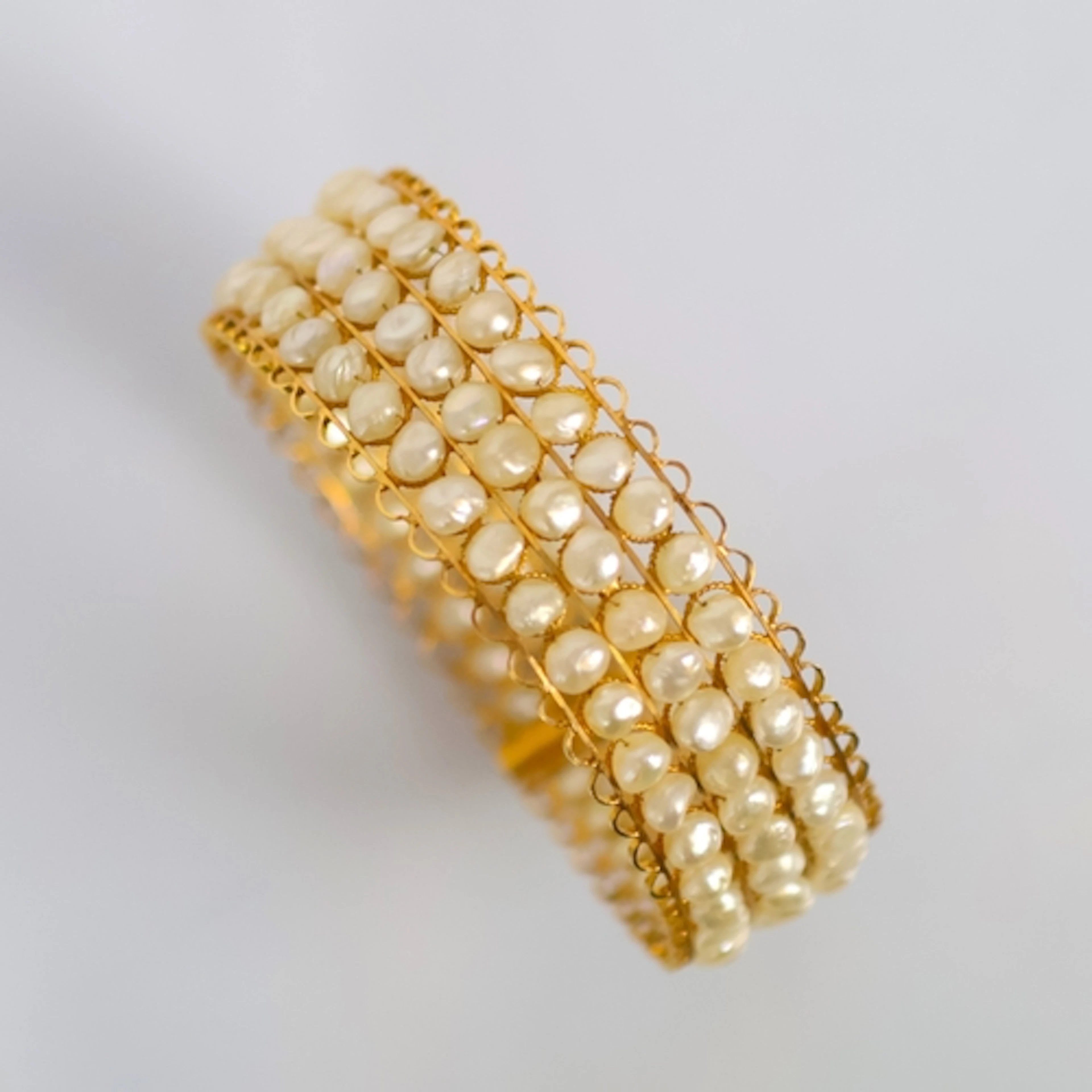 A pearl bangle, probably Middle Eastern, the triple row of p...