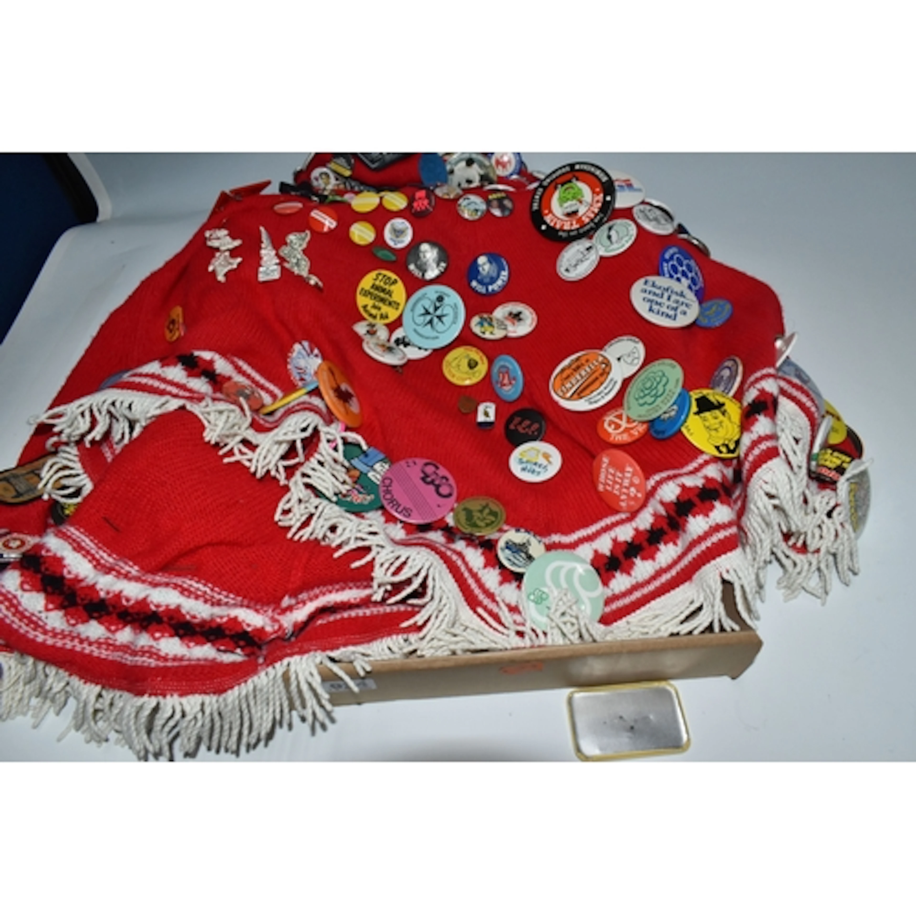 A BOX CONTAINING A WOOLLEN PONCHO FESTOONED WITH VINTAGE PIN...