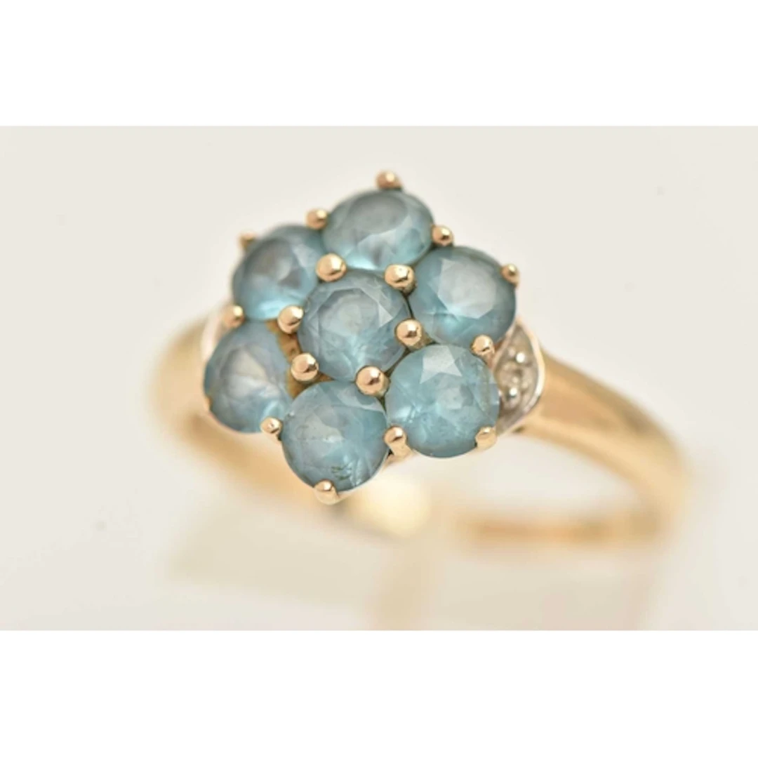 A 9CT YELLOW GOLD GEM SET RING, seven circular cut topaz, fl...