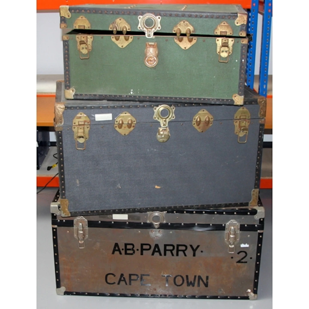 Three large flat topped steamer trunks with metal fastenings...