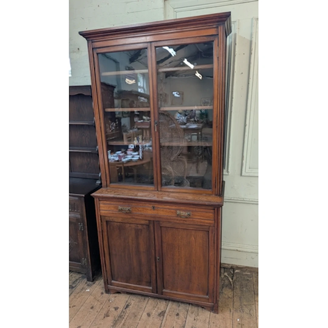 A Edwardian walnut glazed two door bookcase standing on draw...